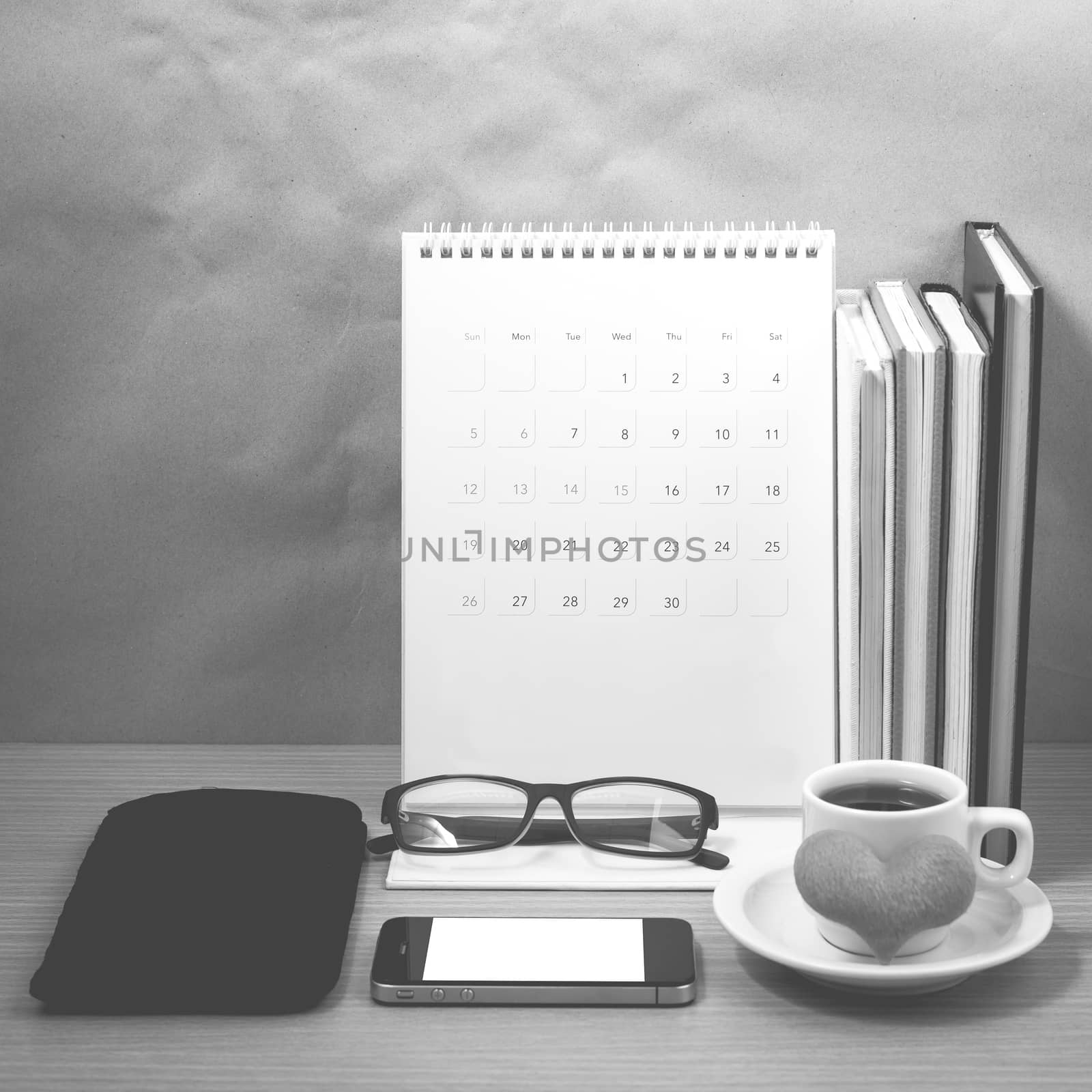 desktop : coffee with phone,stack of book,wallet,heart,eyeglasses,calendar on wood background black and white color