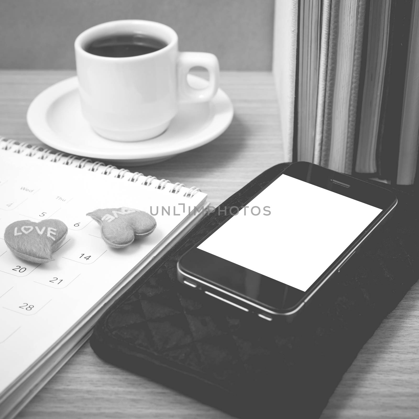 office desk : coffee with phone,wallet,calendar,heart,stack of book on wood background black and white color