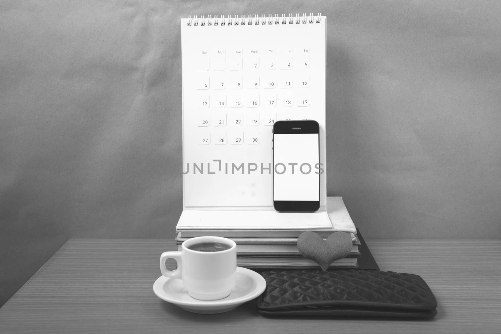 office desk : coffee with phone,wallet,calendar,heart,stack of book on wood background black and white color