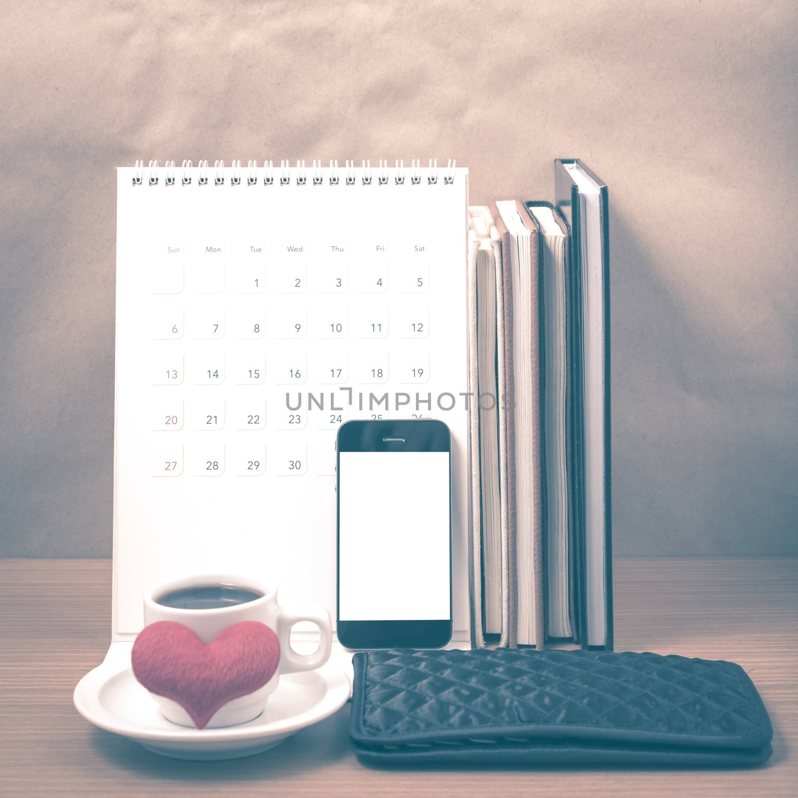 office desk : coffee with phone,wallet,calendar,heart,stack of book on wood background vintage style