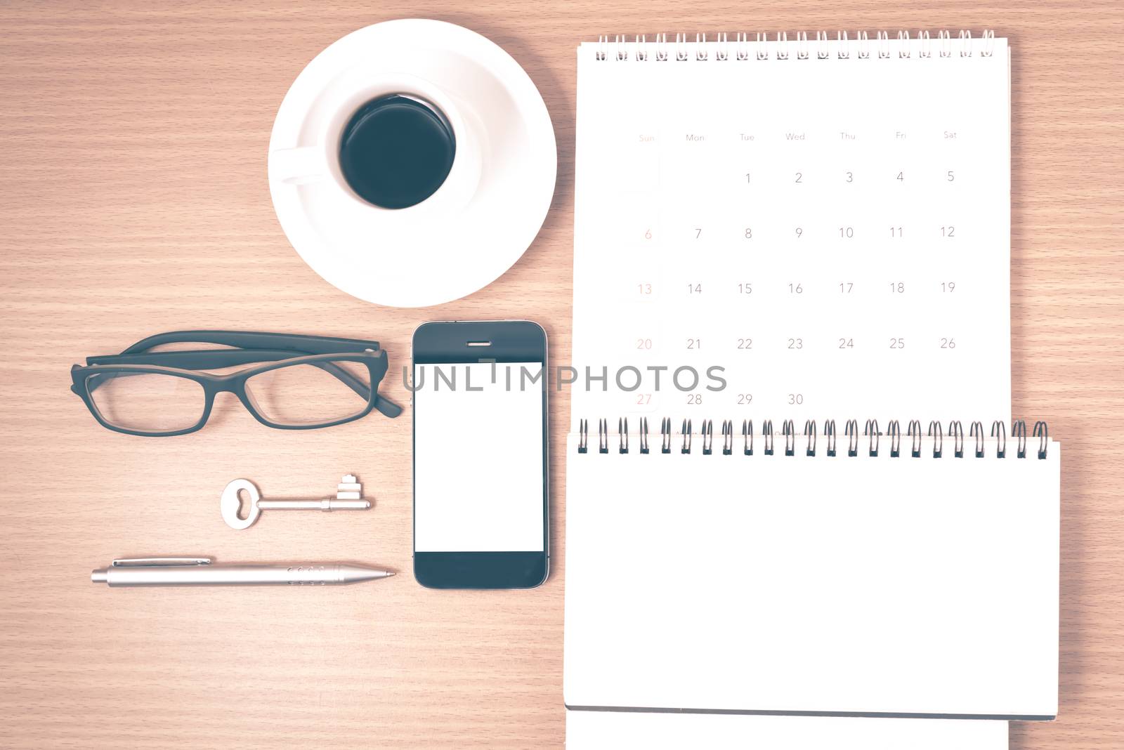 coffee and phone with key,eyeglasses,notepad,calendar on wood table background vintage style