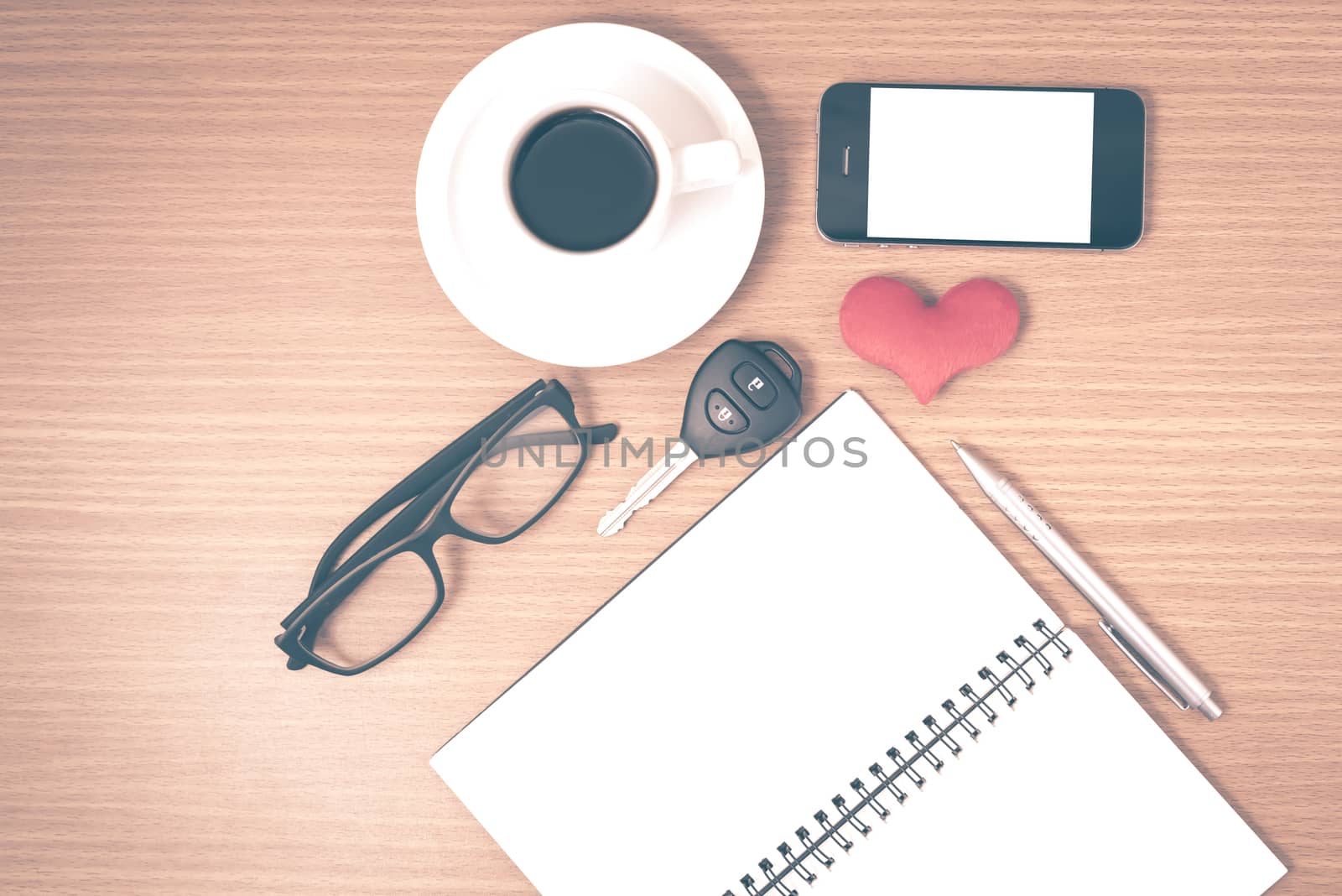 office desk : coffee and phone with car key,eyeglasses,notepad,heart on wood background vintage style