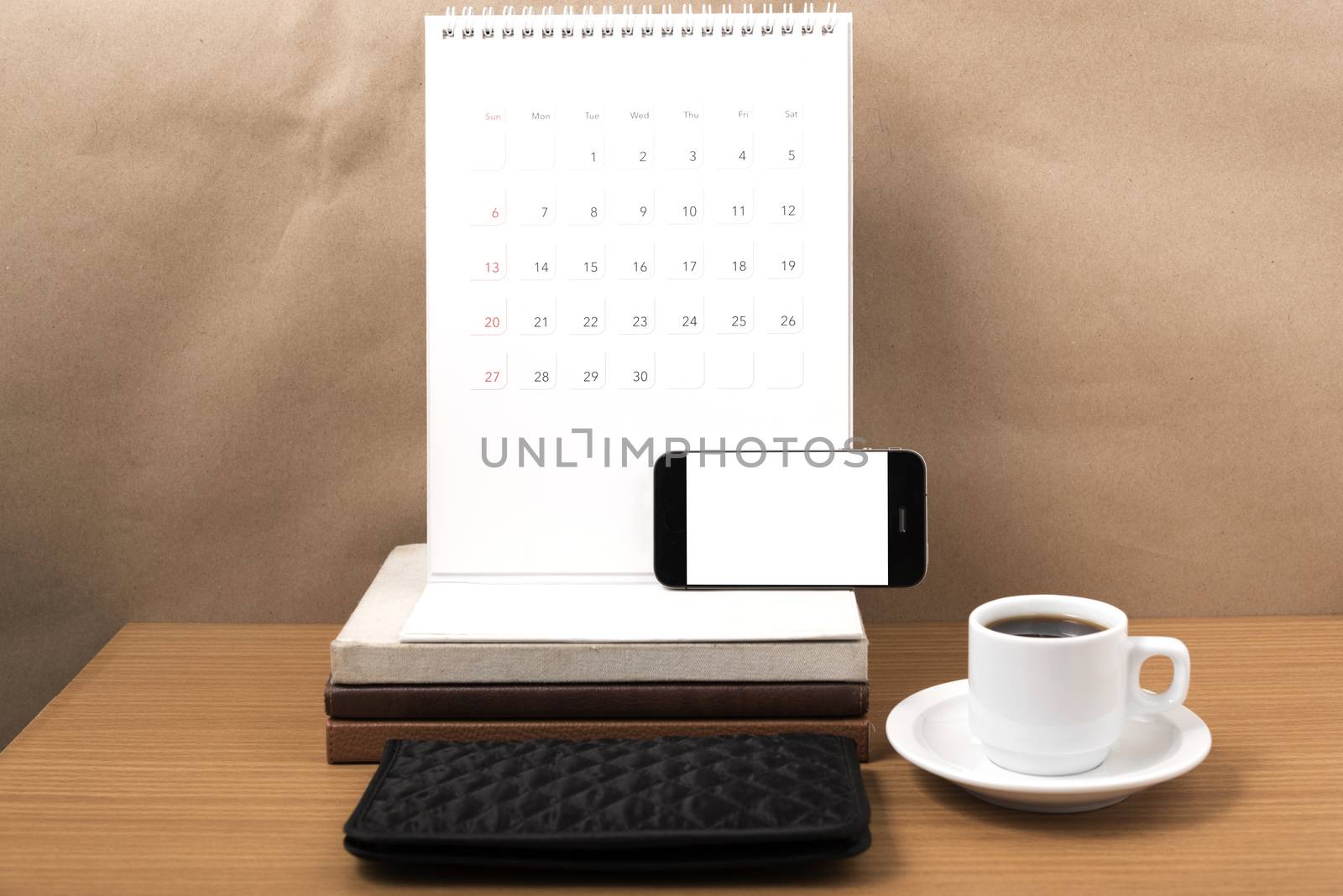 working table : coffee with phone,stack of book and wallet on wood background