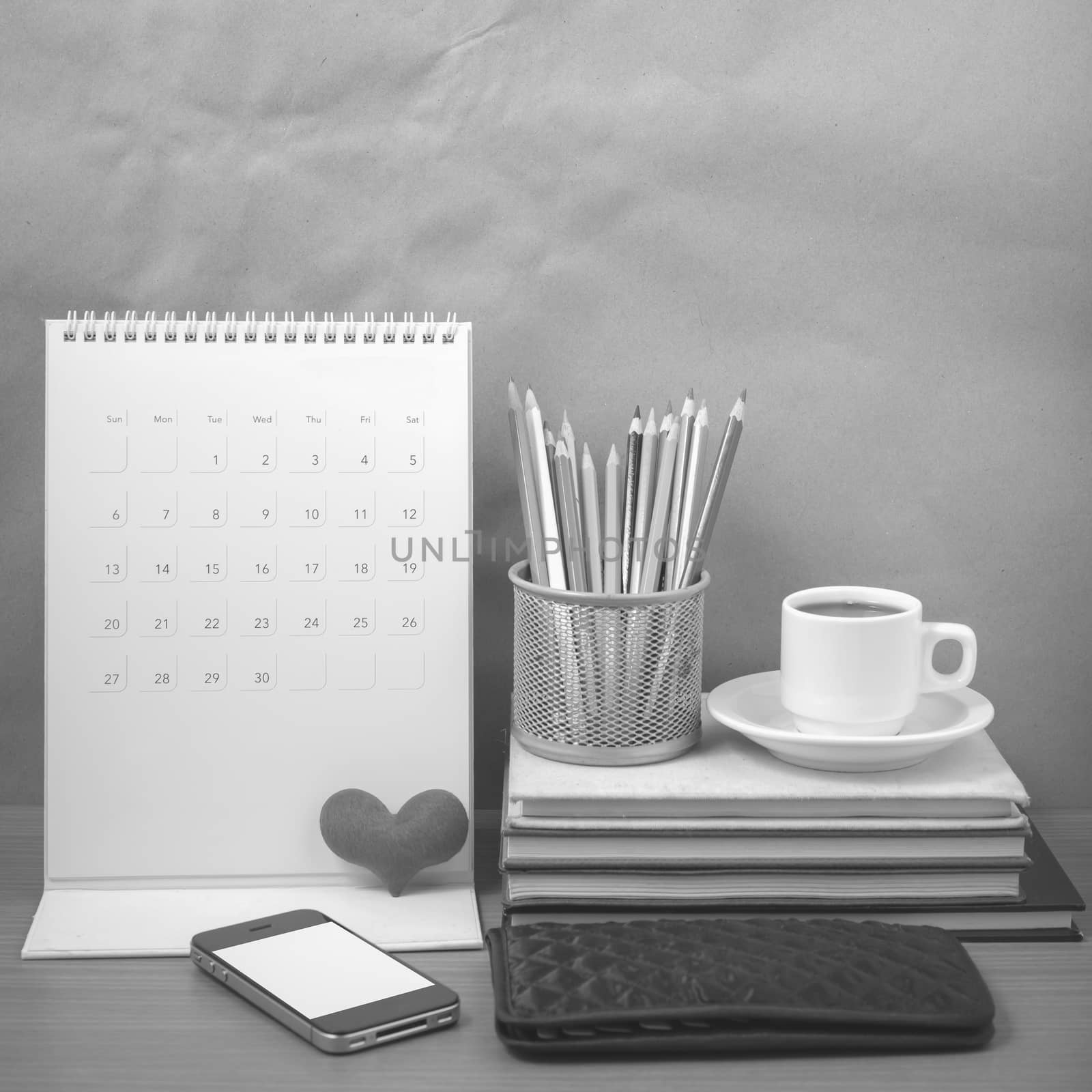 office desk : coffee with phone,wallet,calendar,heart,color pencil box,stack of book,heart on wood background black and white color