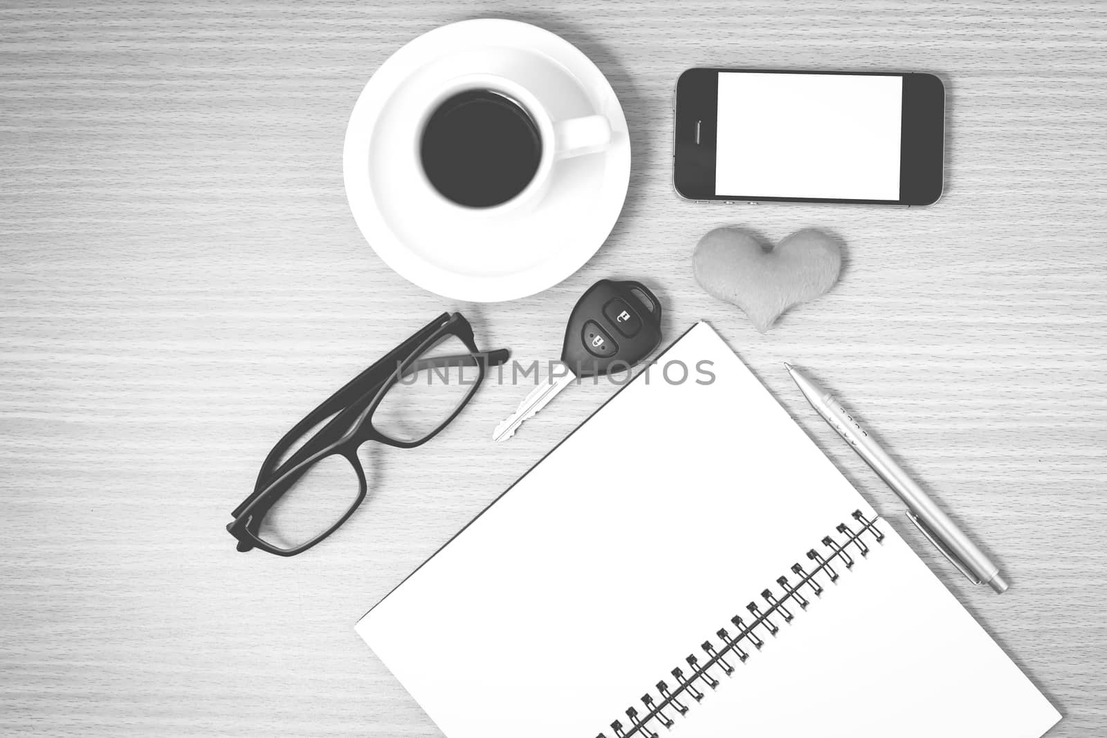 office desk : coffee and phone with car key,eyeglasses,notepad,heart on wood background black and white color