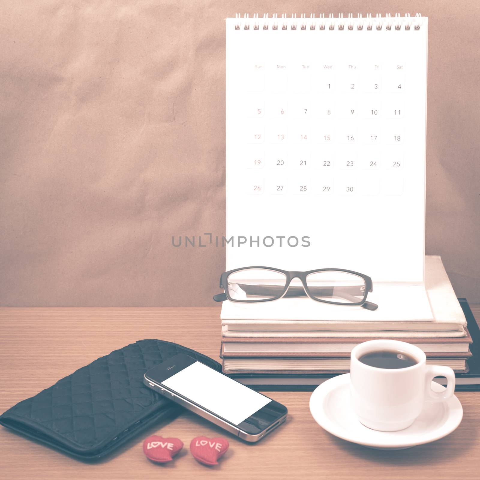office desk : coffee with phone,wallet,calendar,heart,stack of book,eyeglasses on wood background vintage style