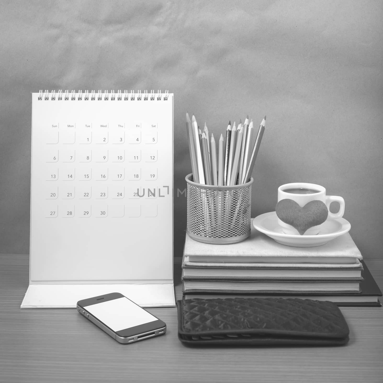 office desk : coffee with phone,wallet,calendar,heart,color pencil box,stack of book,heart on wood background black and white color