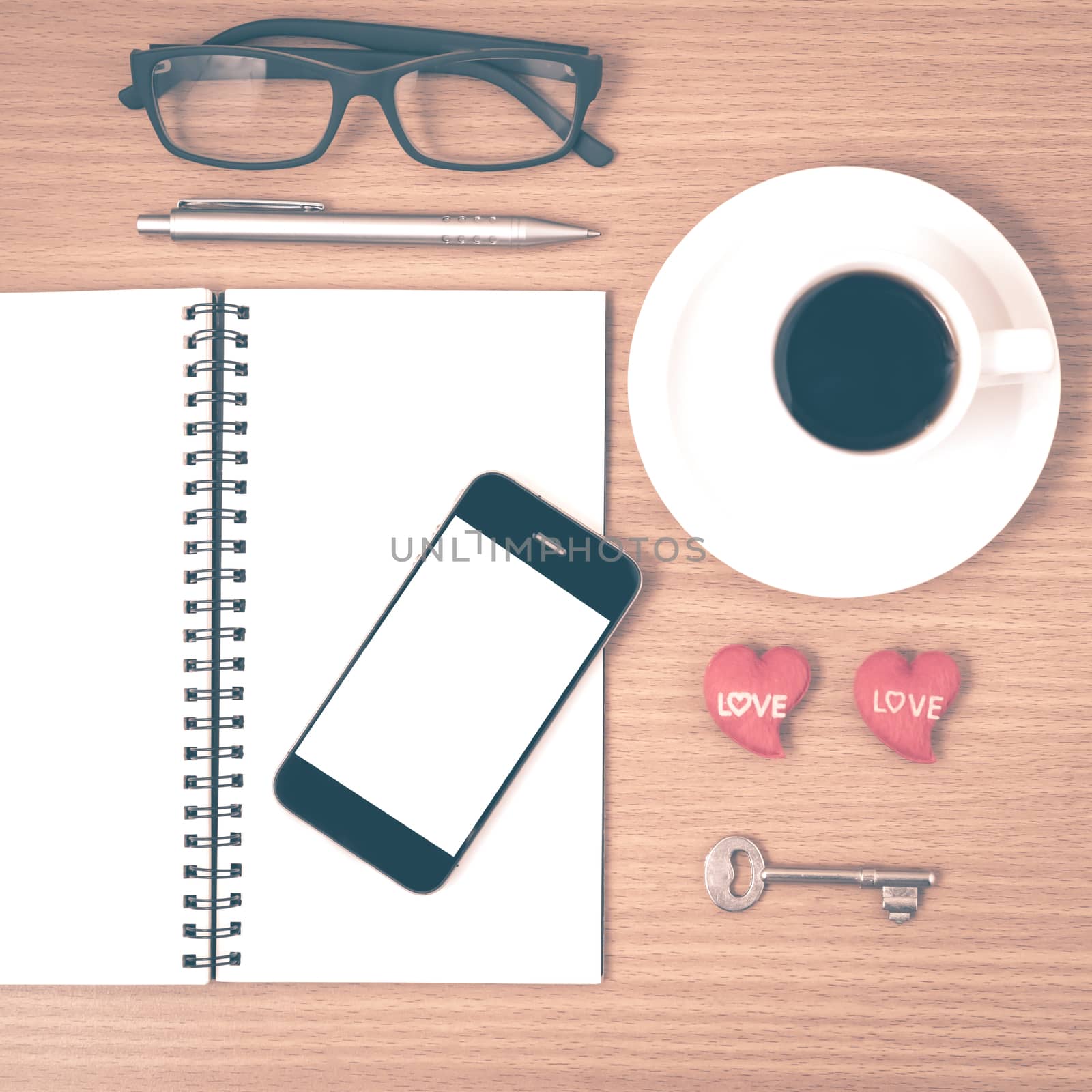 office desk : coffee and phone with key,eyeglasses,notepad,heart on wood background vintage style