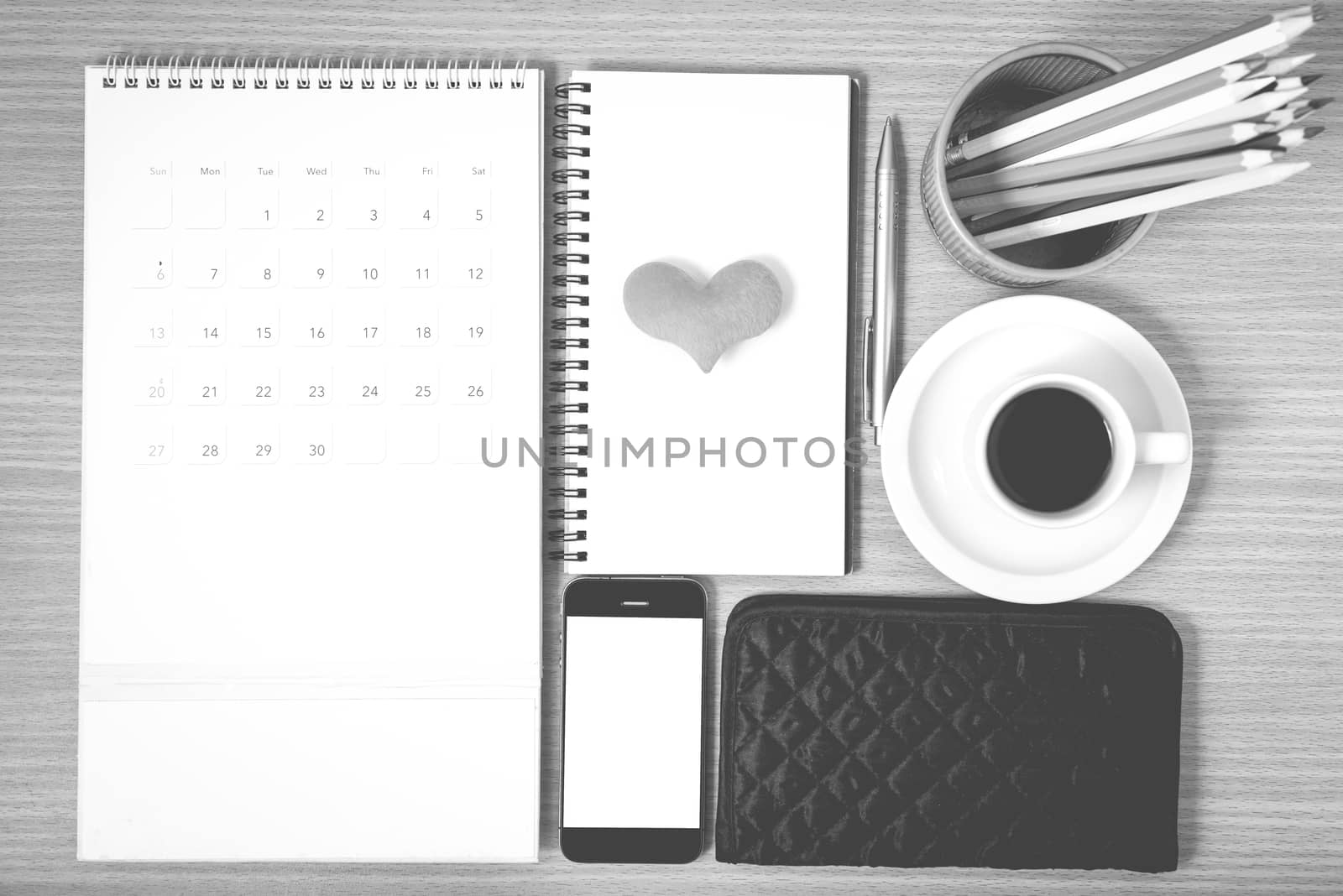 office desk : coffee with phone,wallet,calendar,heart,color pencil box,notepad,heart on wood background black and white color