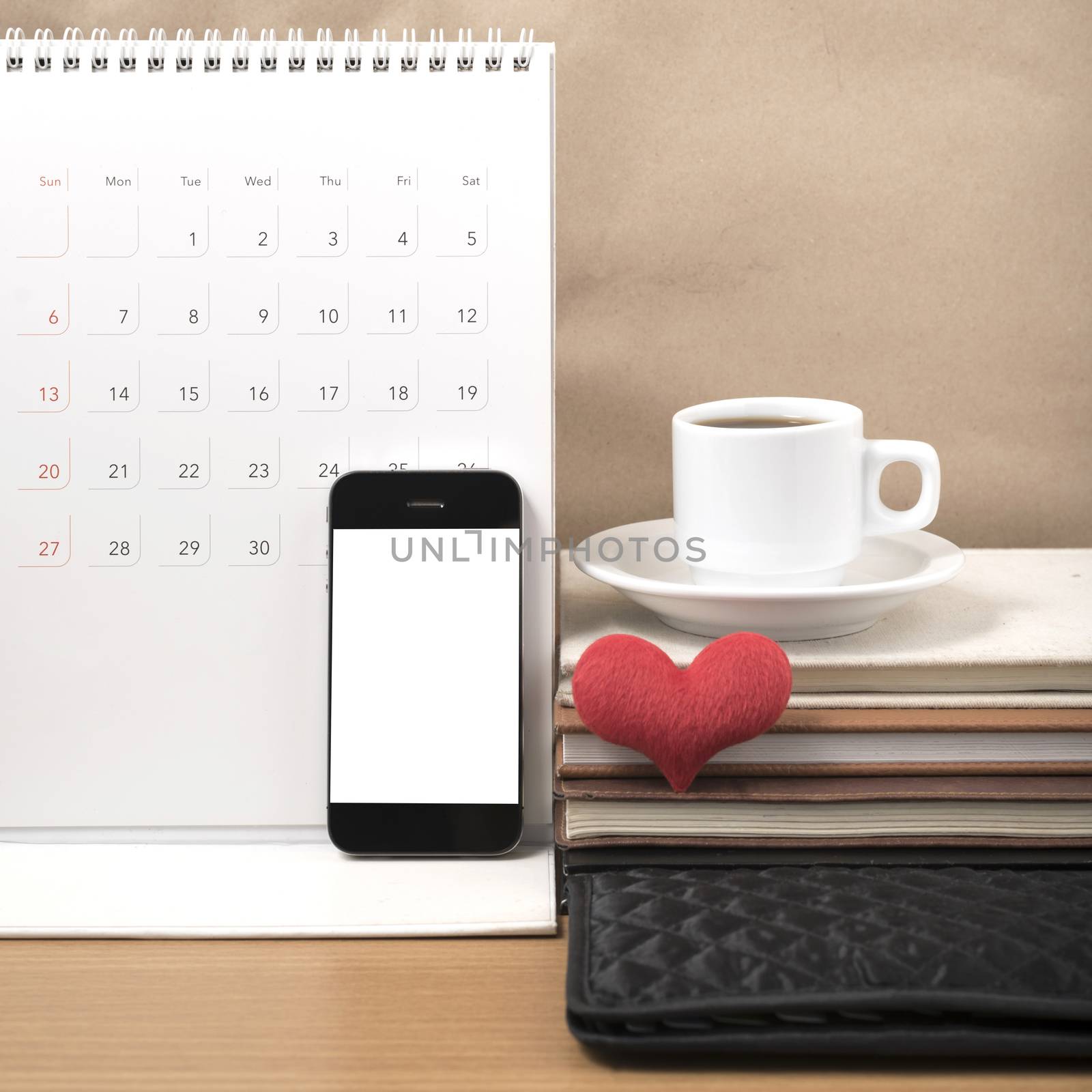 office desk : coffee with phone,wallet,calendar,heart,stack of book on wood background