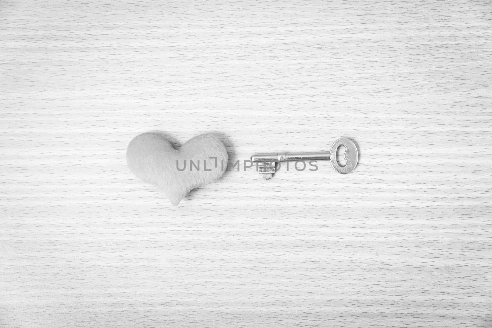 red heart with key on wood table background black and white color