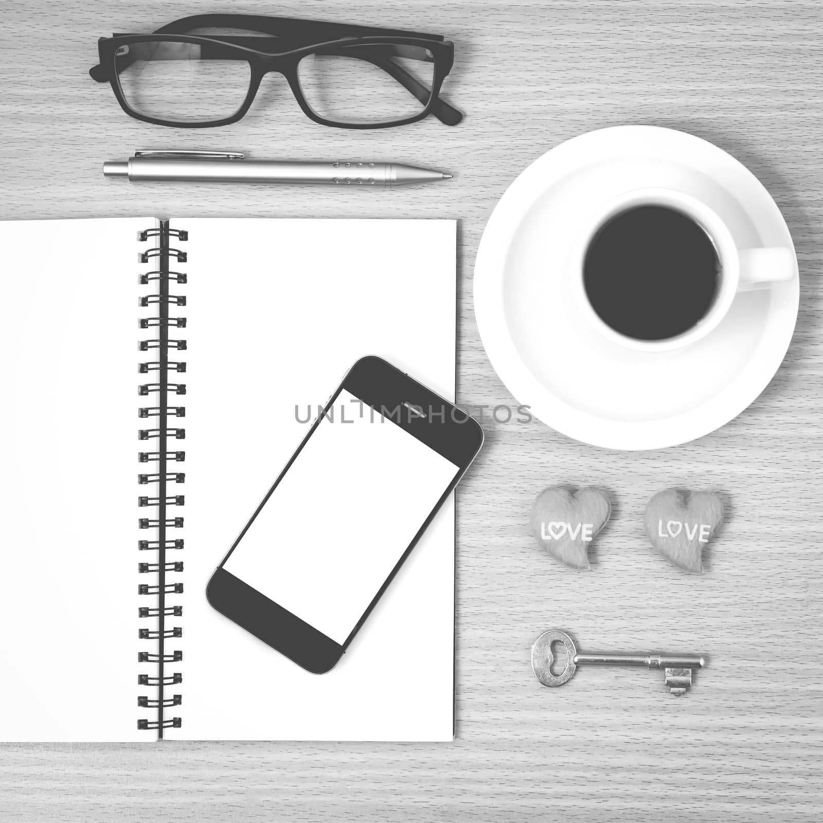 office desk : coffee and phone with key,eyeglasses,notepad,heart on wood background black and white color