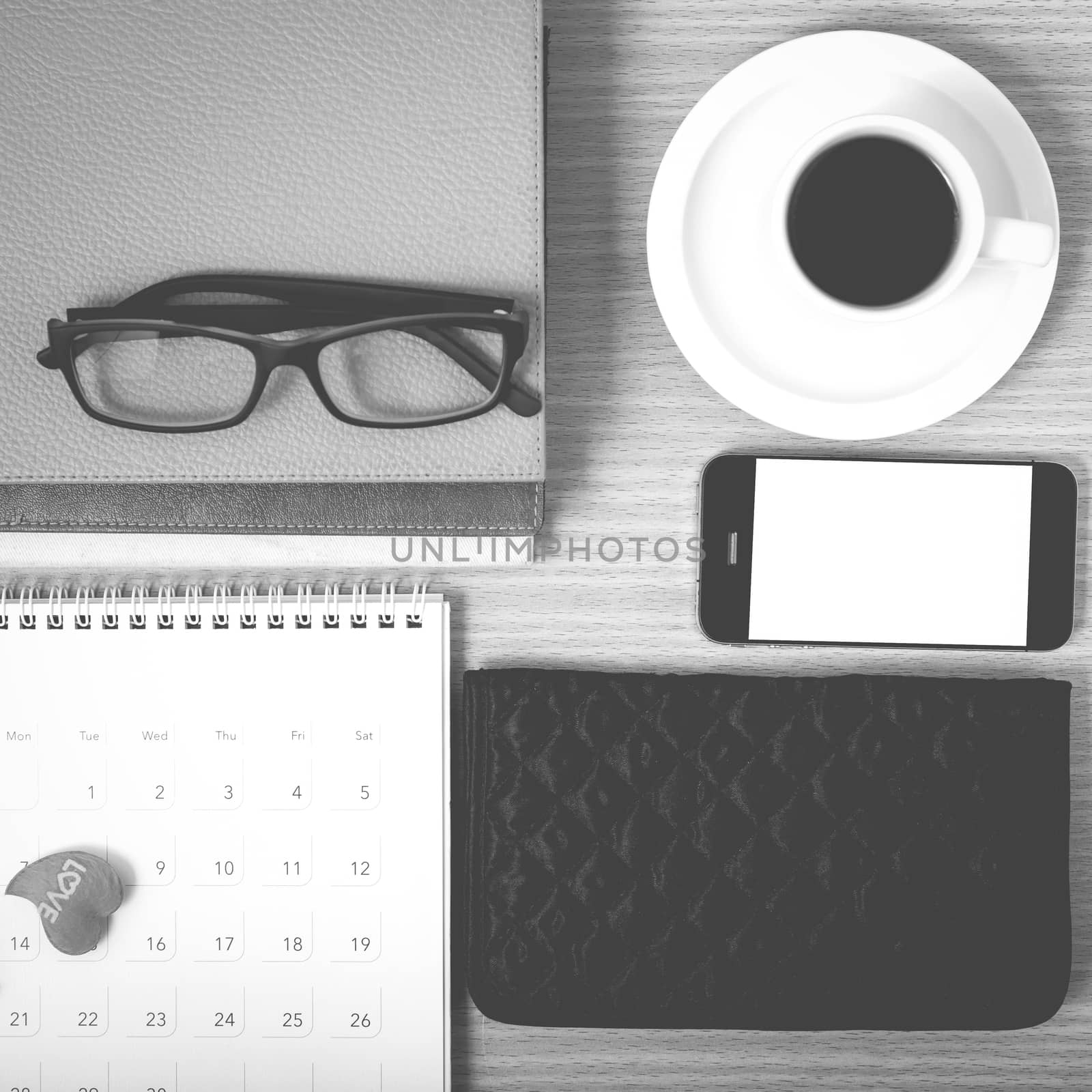 office desk : coffee with phone,stack of book,eyeglasses,wallet,calendar,heart on wood background black and white color