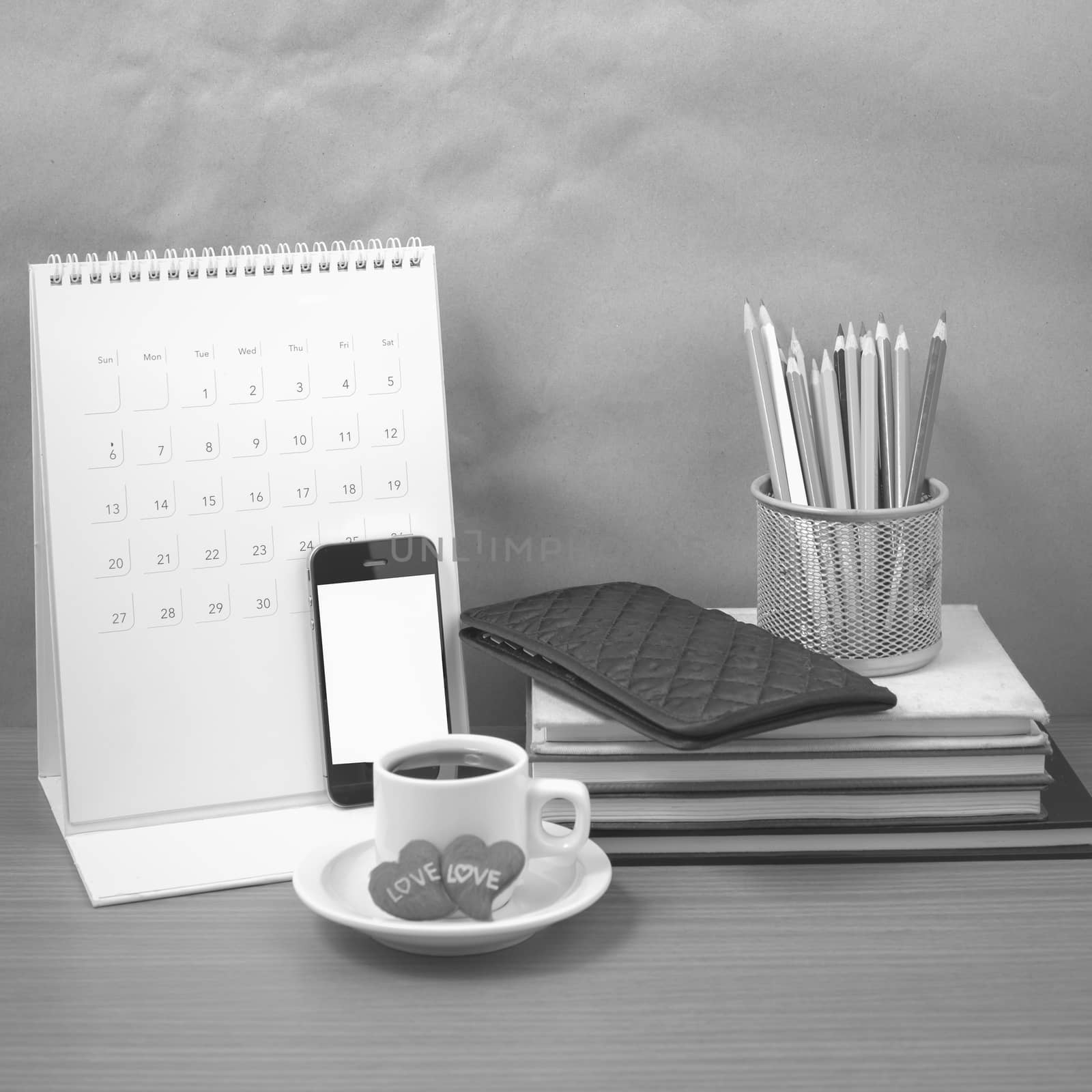 office desk : coffee with phone,wallet,calendar,heart,color pencil box,stack of book,heart on wood background black and white color