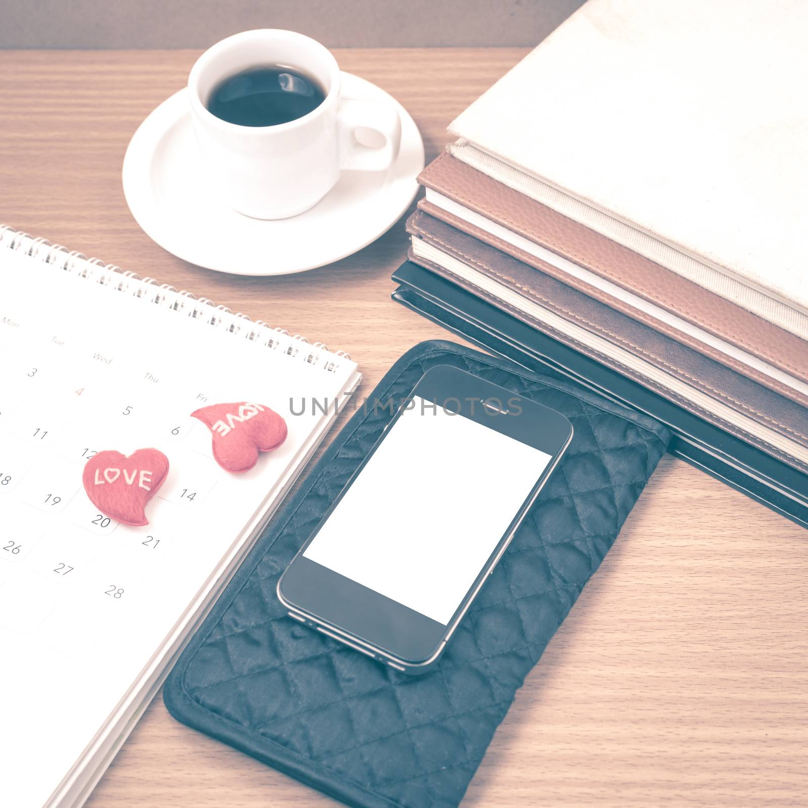 office desk : coffee with phone,wallet,calendar,heart,stack of book on wood background vintage style