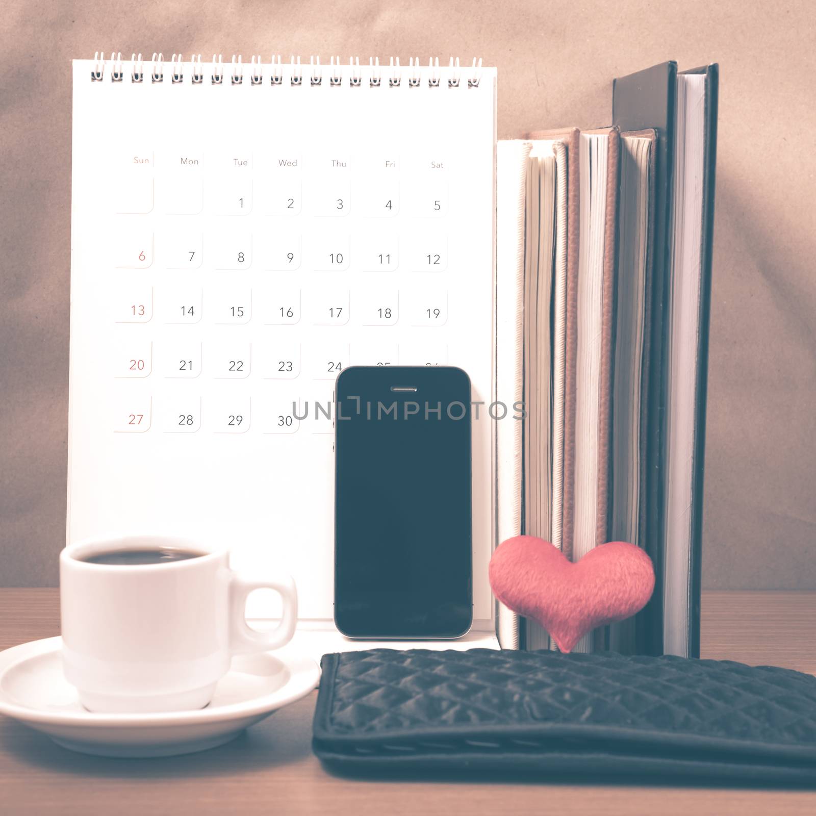 office desk : coffee with phone,wallet,calendar,heart,stack of book on wood background vintage style