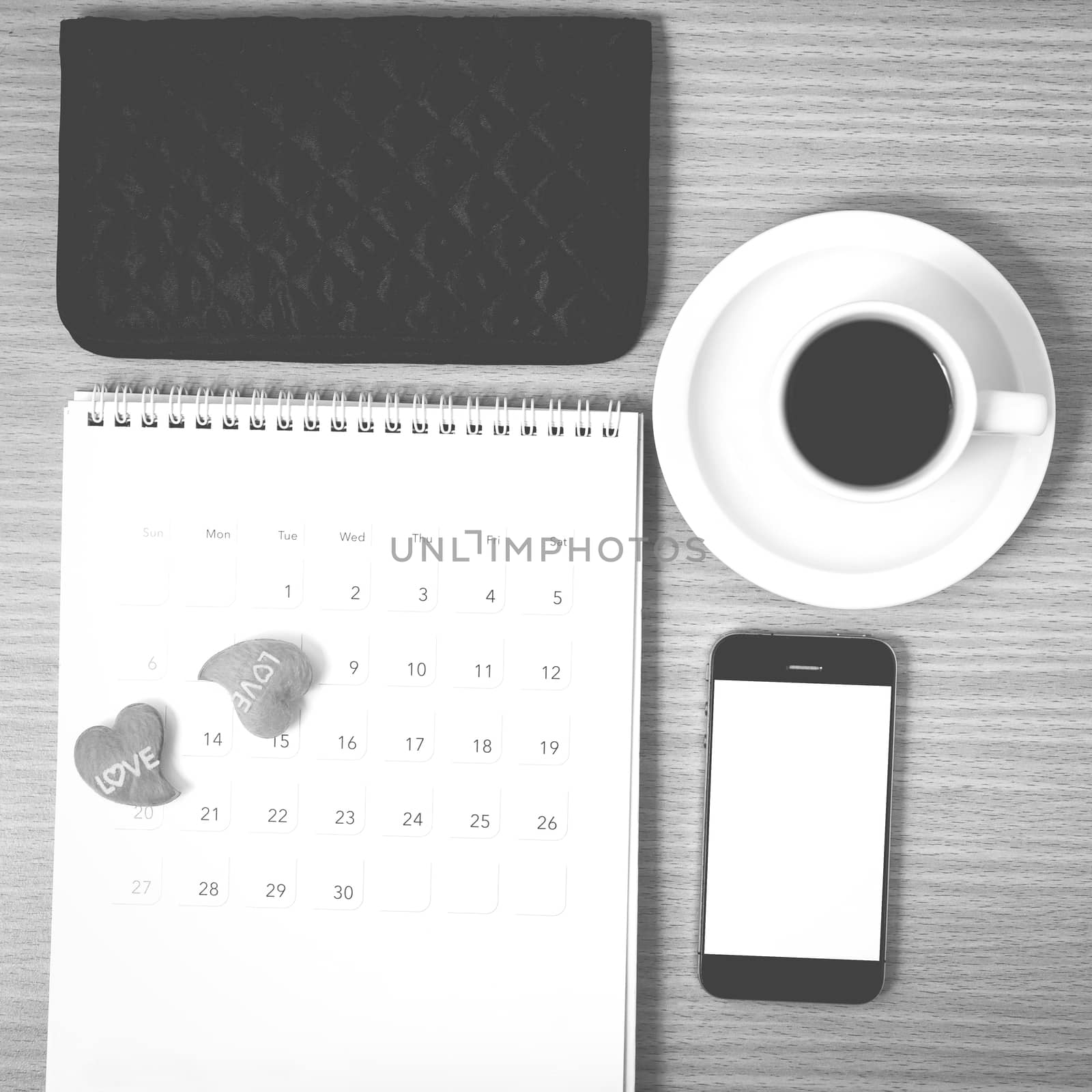 office desk : coffee with phone,calendar,wallet,heart on wood background black and white color