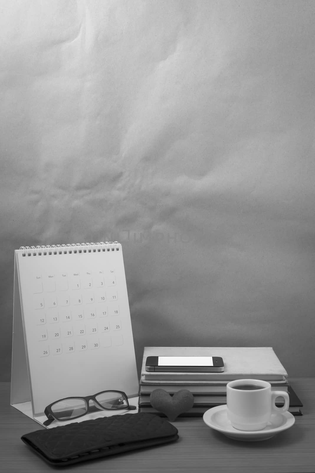 desktop : coffee with phone,stack of book,wallet,heart,eyeglasses,calendar on wood background black and white color