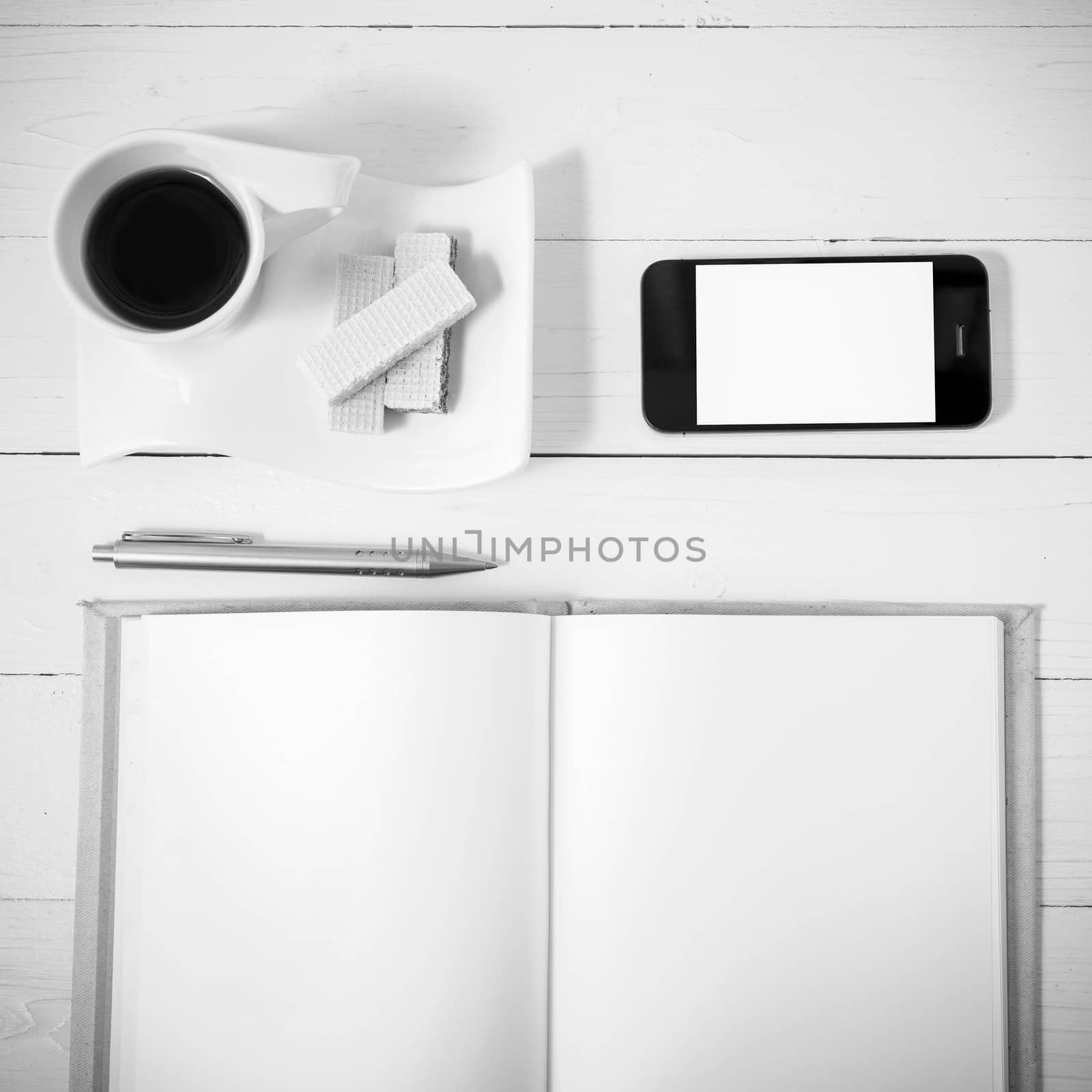 coffee cup with wafer,phone,notebook on white wood background black and white color