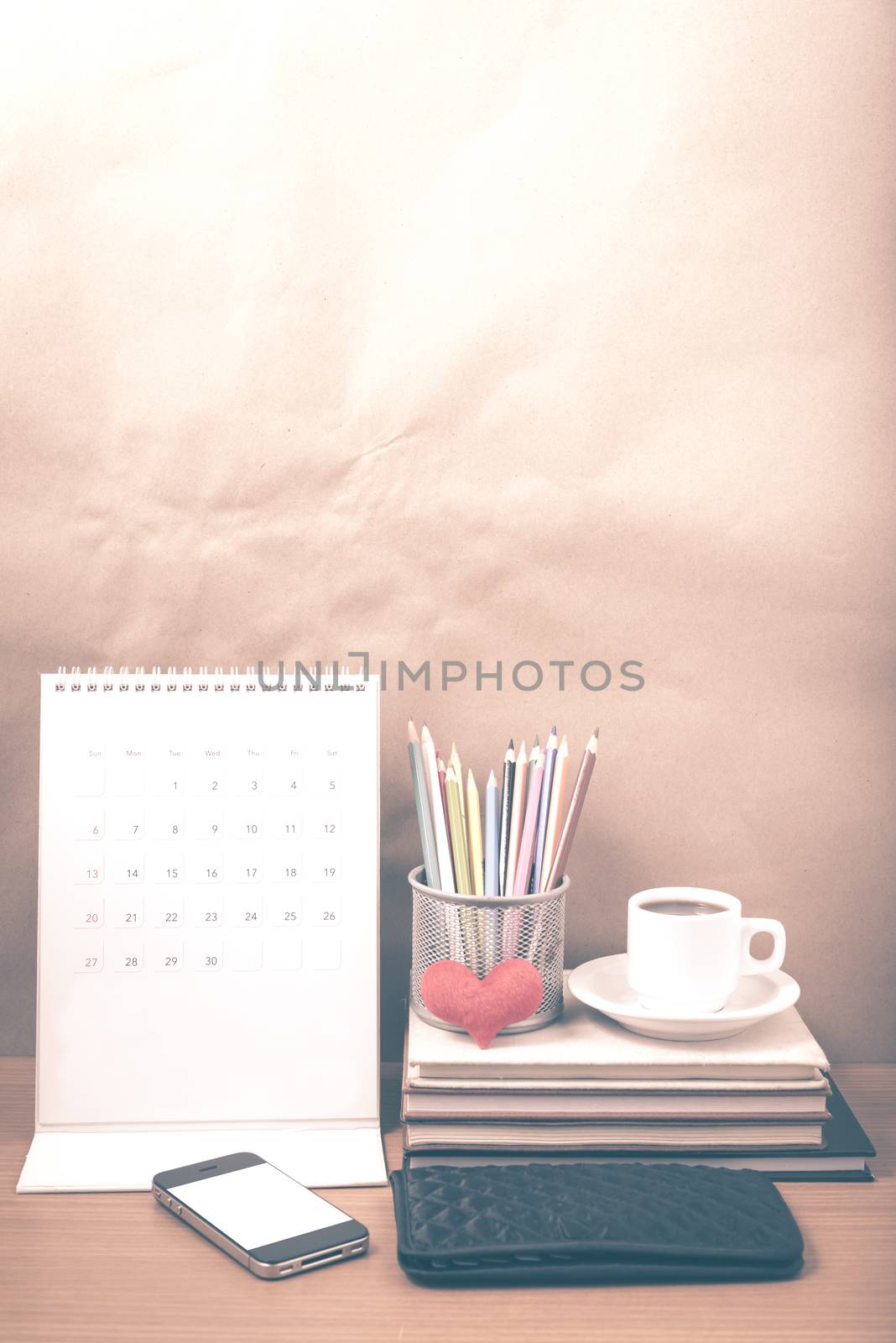 office desk : coffee with phone,wallet,calendar,heart,color pencil box,stack of book,heart on wood background vintage style