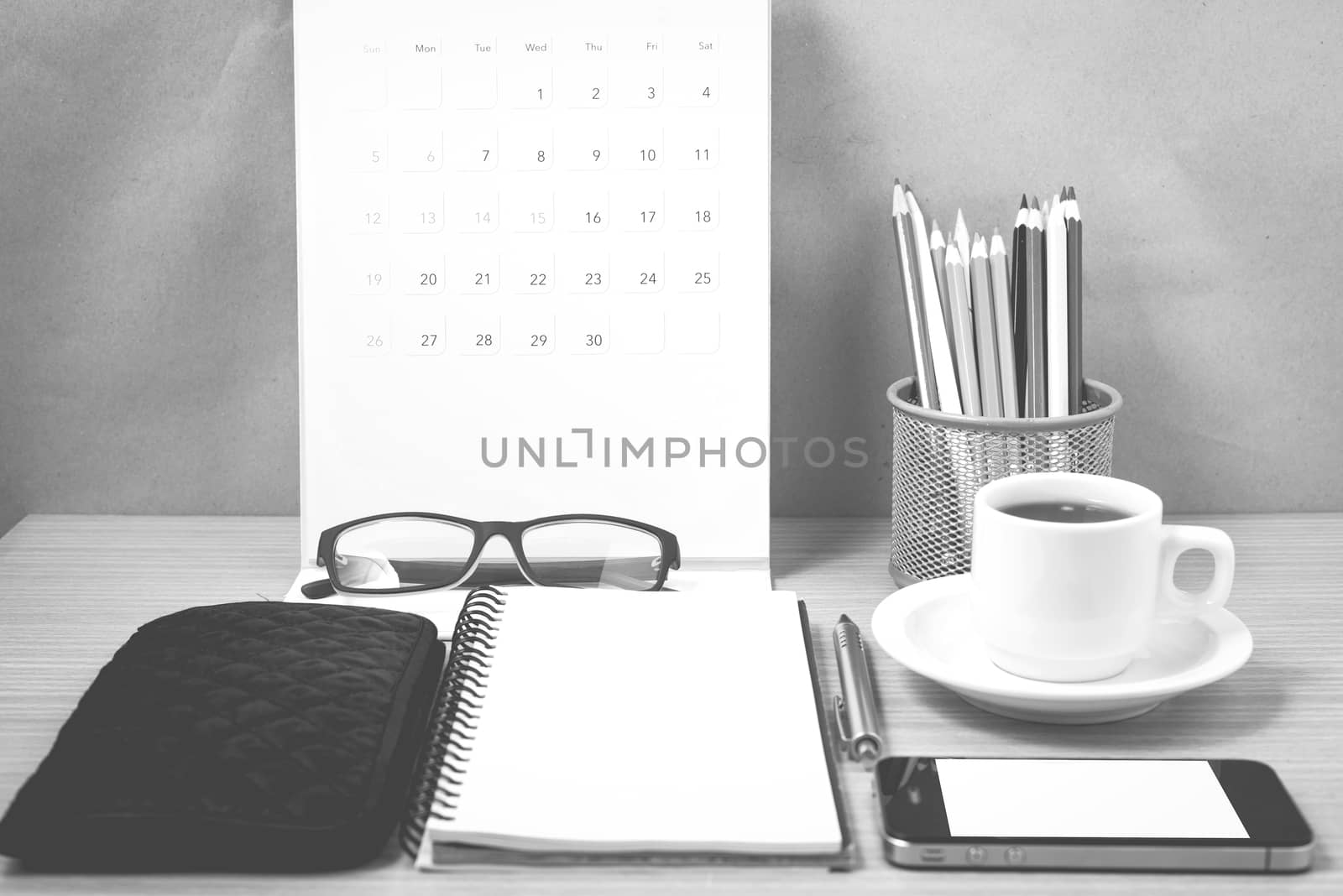 office desk : coffee with phone,wallet,calendar,heart,notepad,eyeglasses,color pencil box on wood background black and white color