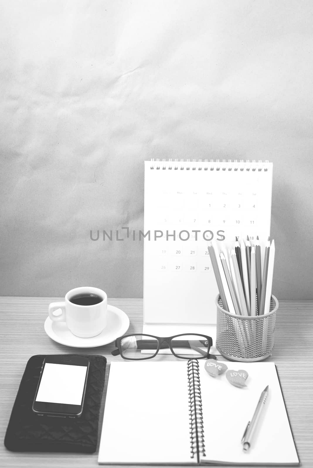 office desk : coffee with phone,wallet,calendar,color pencil box,notepad,heart on wood background black and white color