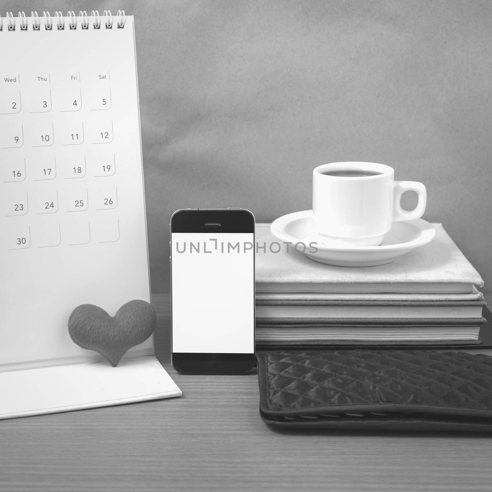 office desk : coffee with phone,wallet,calendar,heart,stack of book on wood background black and white color