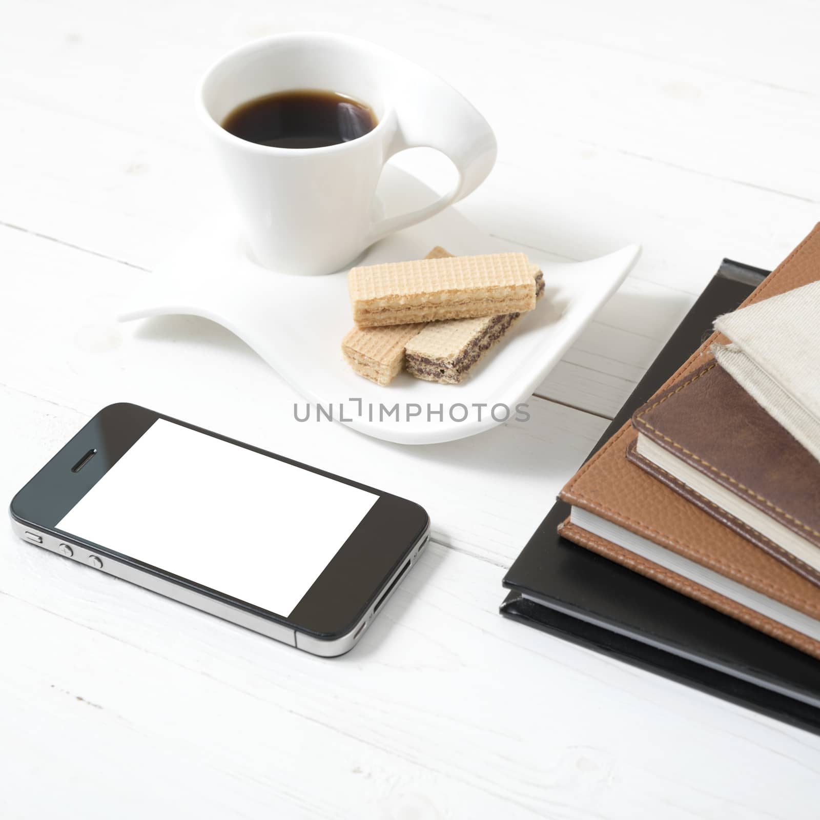 coffee cup with wafer,phone,stack of book on white wood background