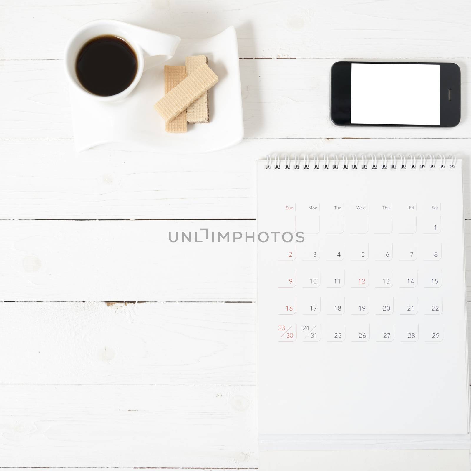 coffee cup with wafer,phone,calendar on white wood background