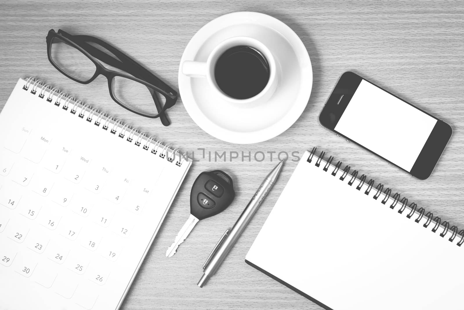 coffee and phone with car key,eyeglasses,notepad,calendar on wood background black and white color