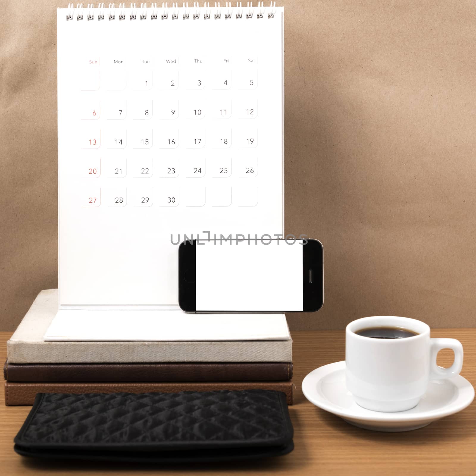 working table : coffee with phone,stack of book and wallet on wood background