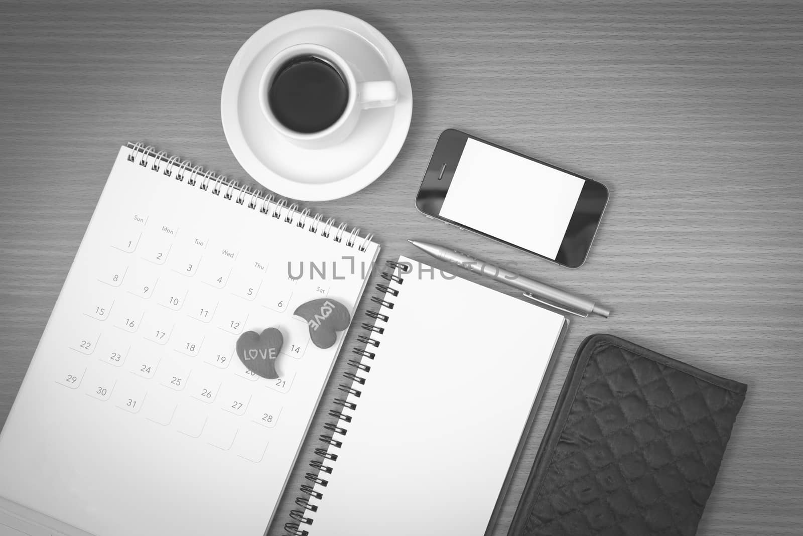 office desk : coffee with phone,wallet,calendar,heart,notepad on wood background black and white color