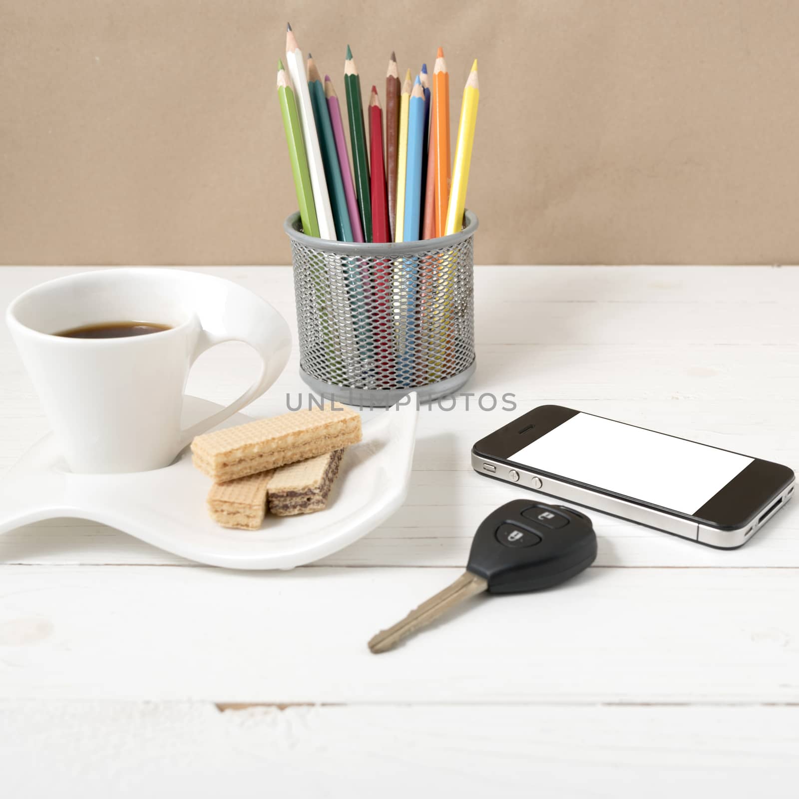 coffee cup with wafer,phone,pencil box,car key on white wood background