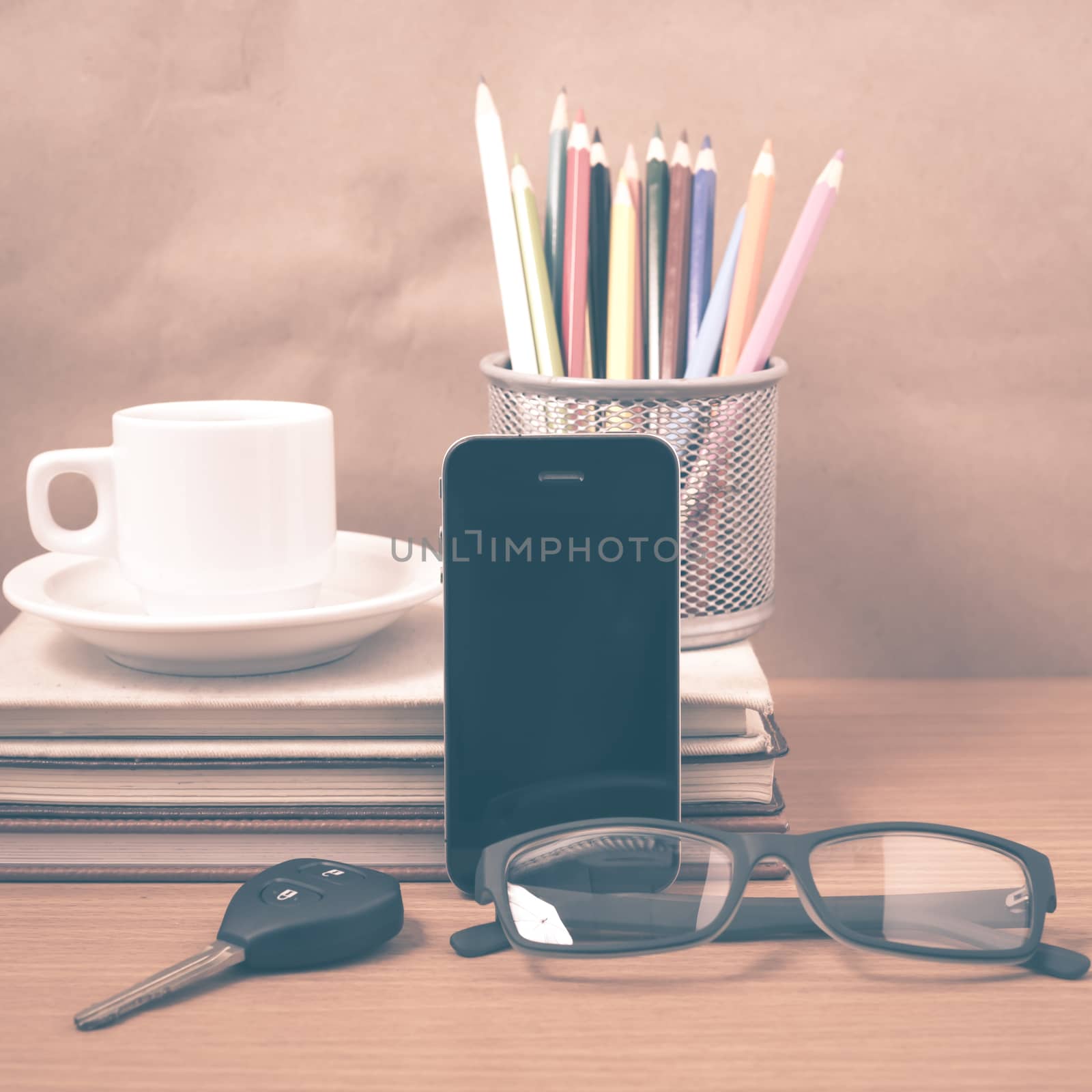office desk : coffee and phone with car key,eyeglasses,stack of book,pencil box vintage style