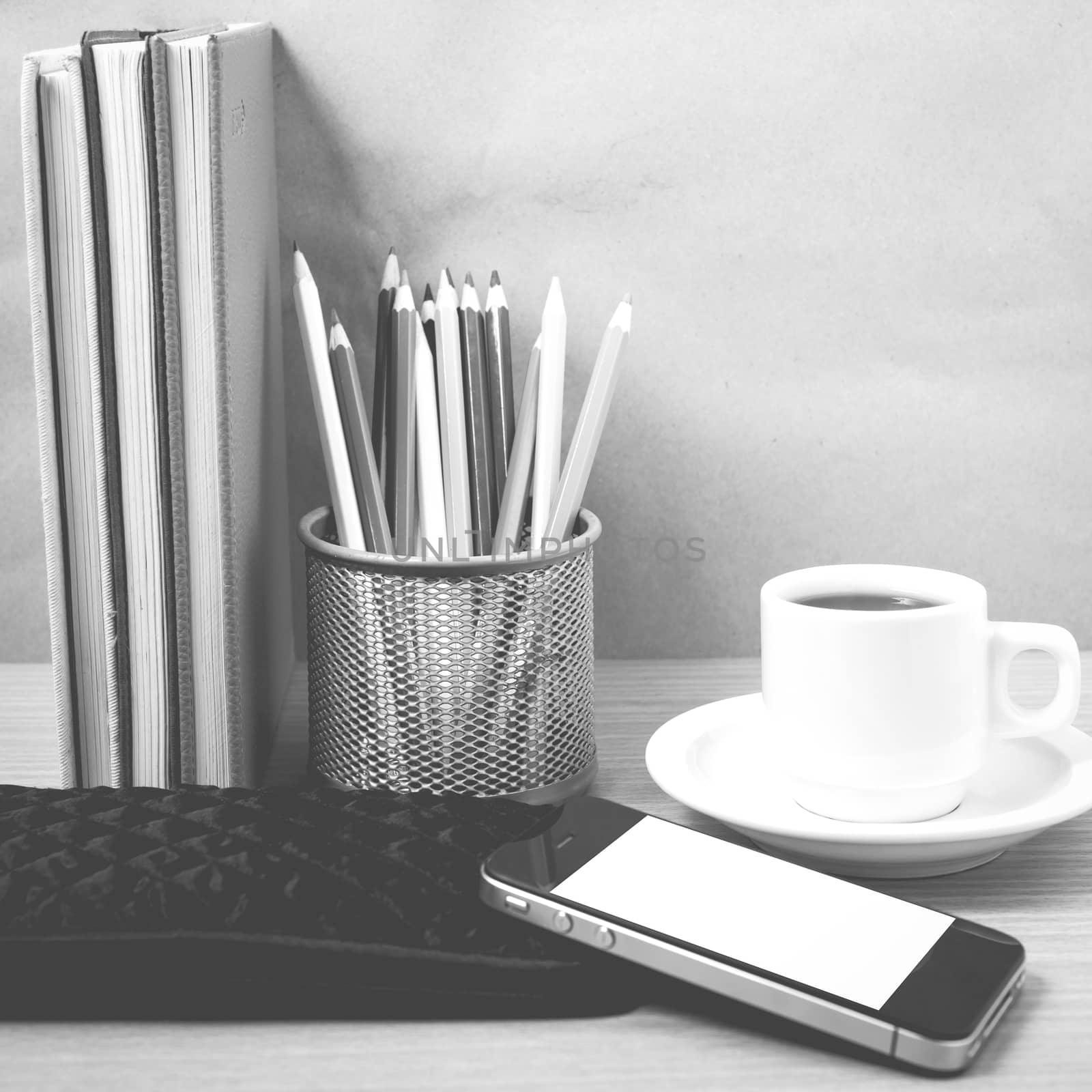 office desk : coffee with phone,stack of book,wallet,color box on wood background black and white color