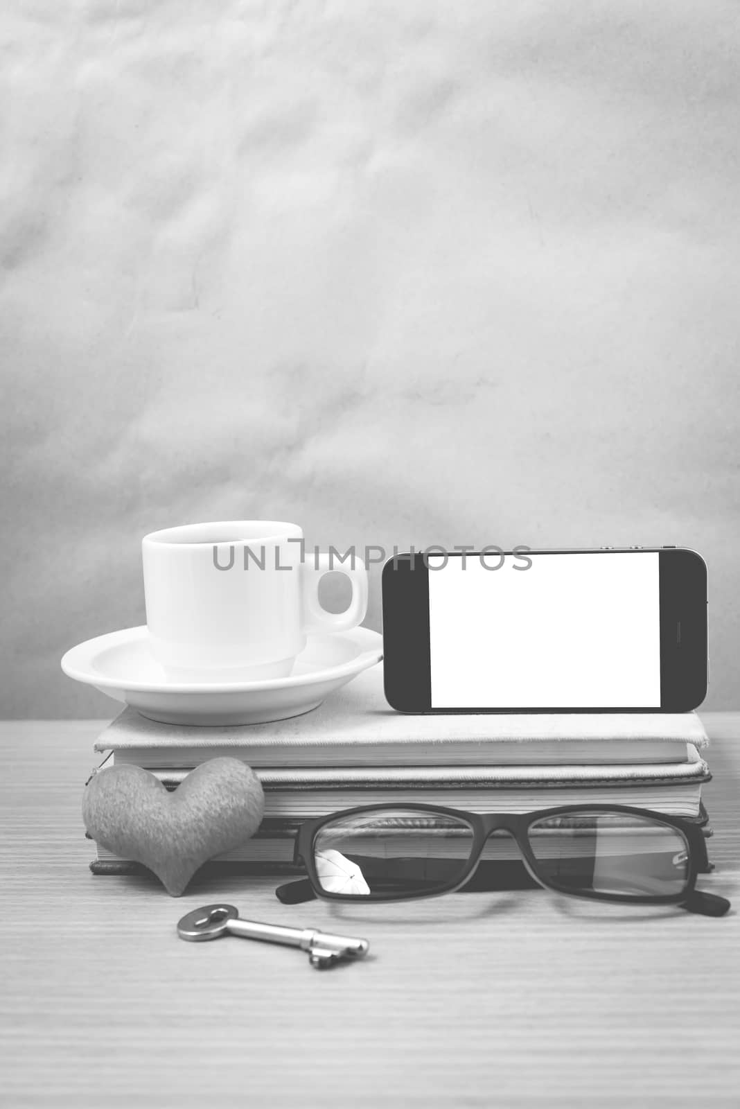 office desk : coffee and phone with key,eyeglasses,stack of book,heart on wood background black and white color