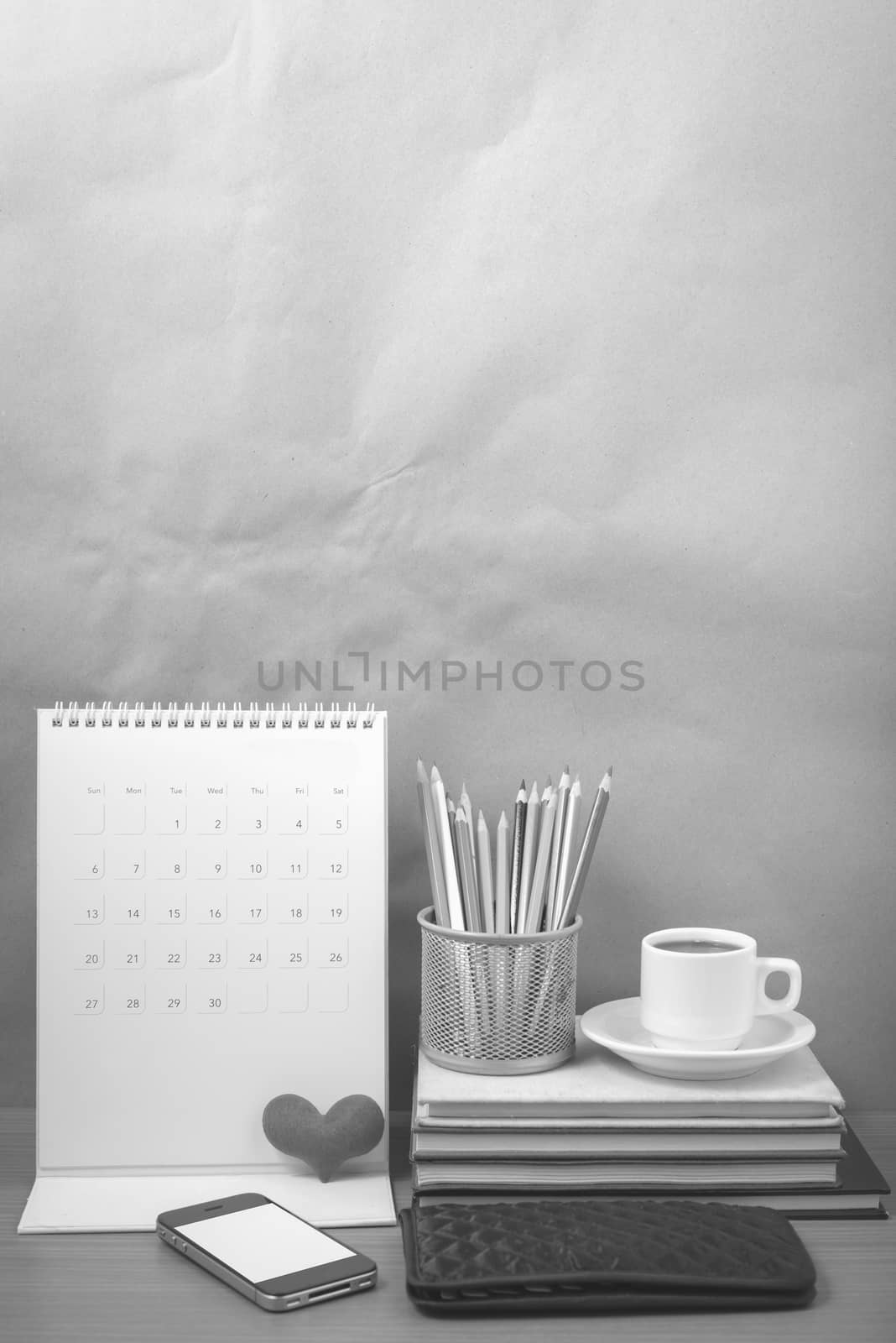 office desk : coffee with phone,wallet,calendar,heart,color pencil box,stack of book,heart on wood background black and white color