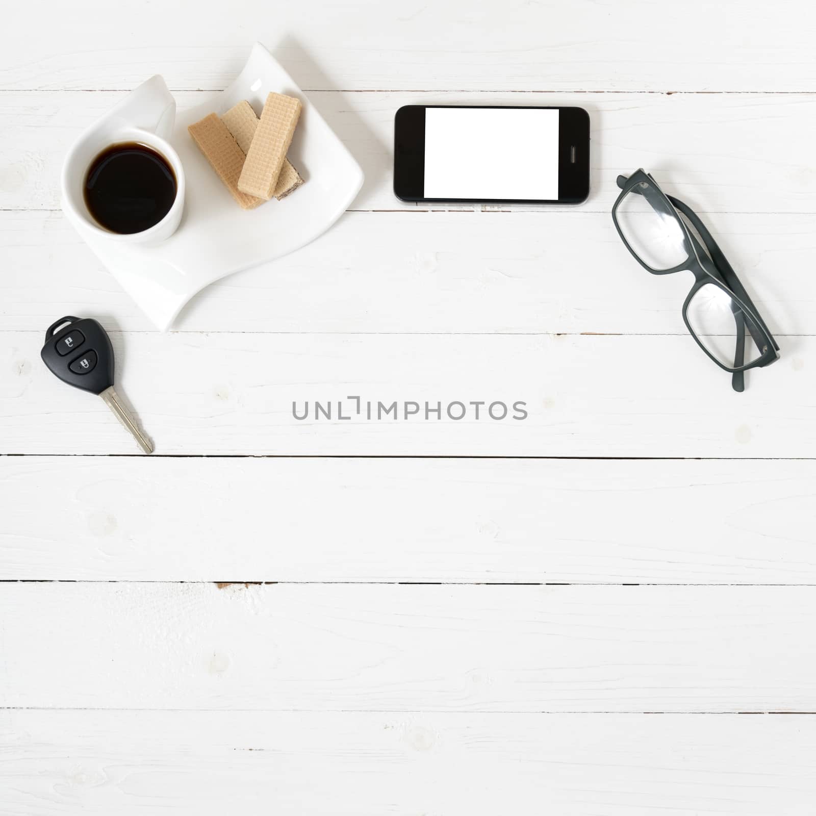 coffee cup with wafer,phone,car key,eyeglasses on white wood background