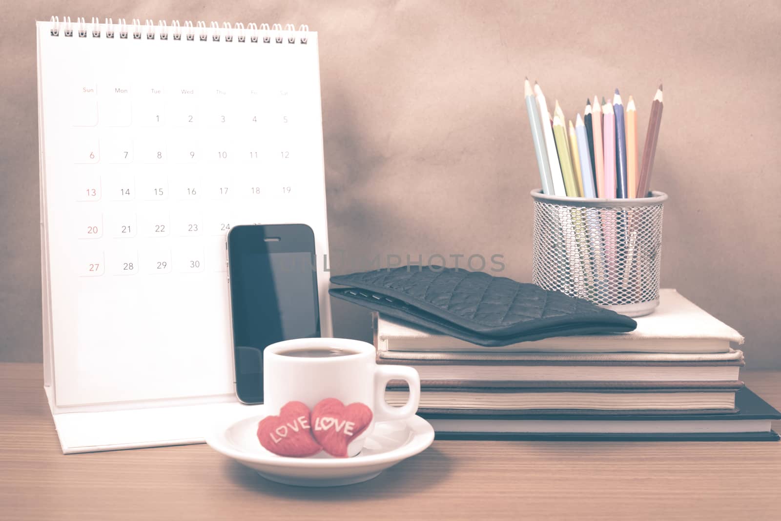 office desk : coffee with phone,wallet,calendar,heart,color pencil box,stack of book,heart on wood background vintage style