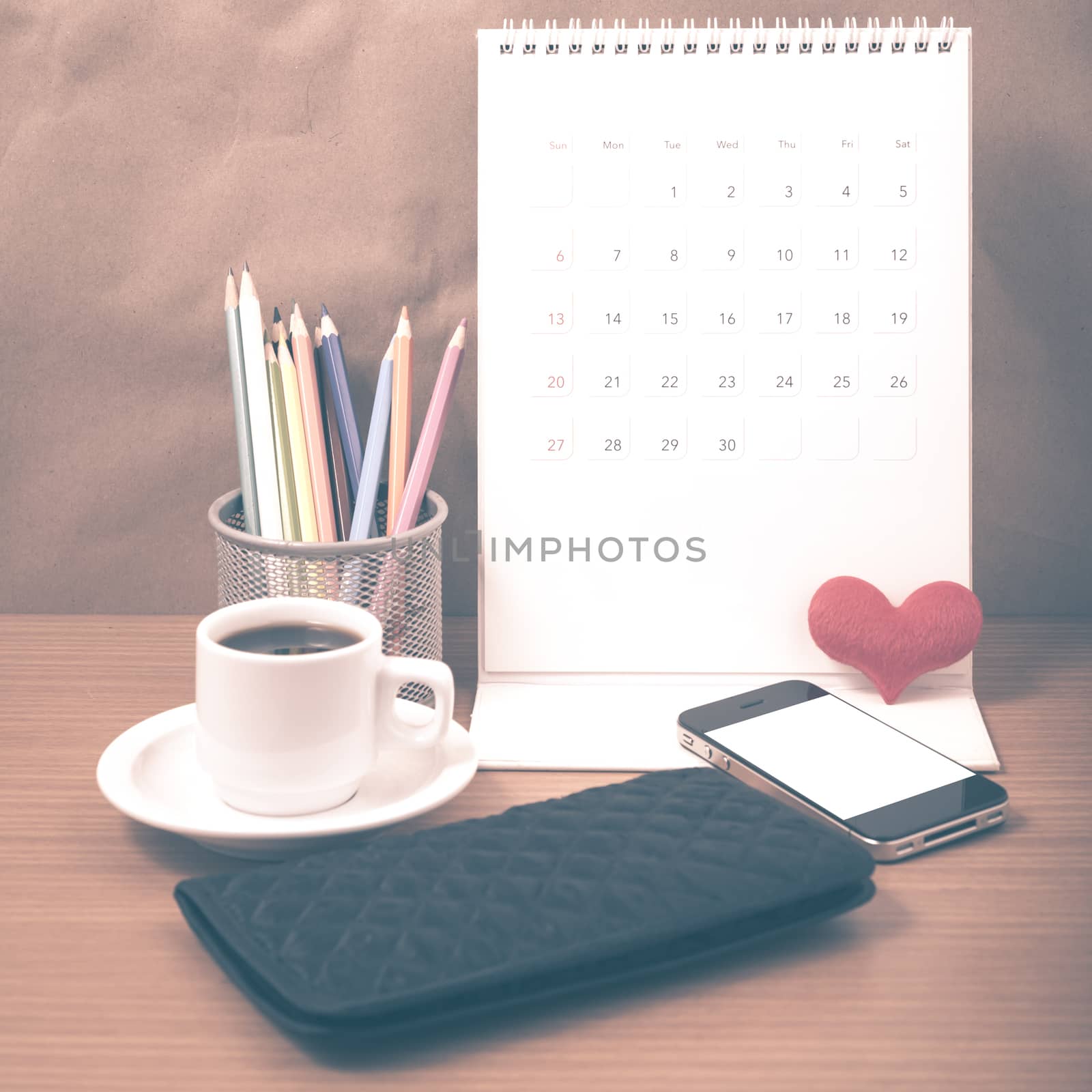 office desk : coffee with phone,wallet,calendar,heart,color pencil box on wood background vintage style