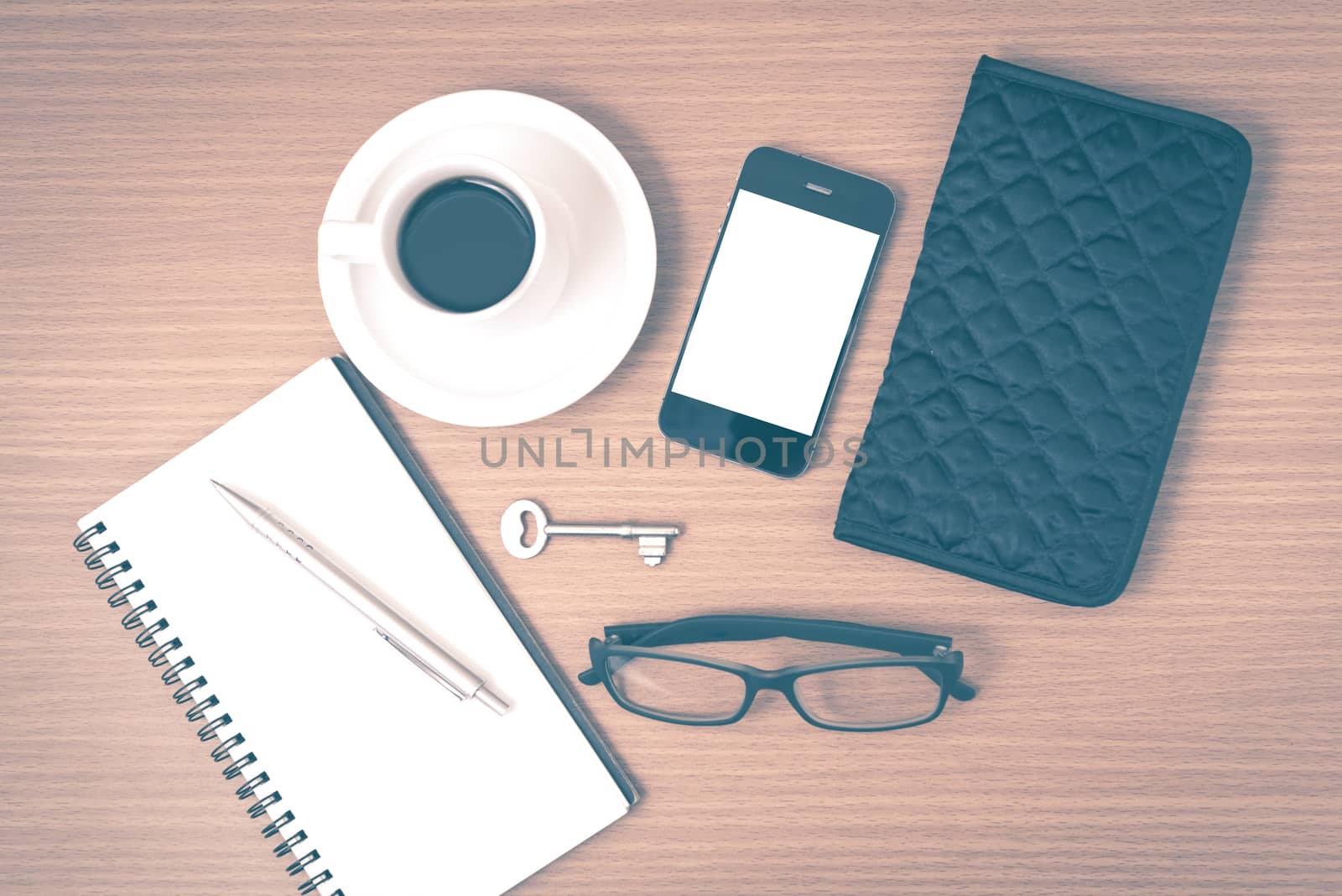 coffee and phone with notepad,key,eyeglasses and wallet on wood table background vintage style