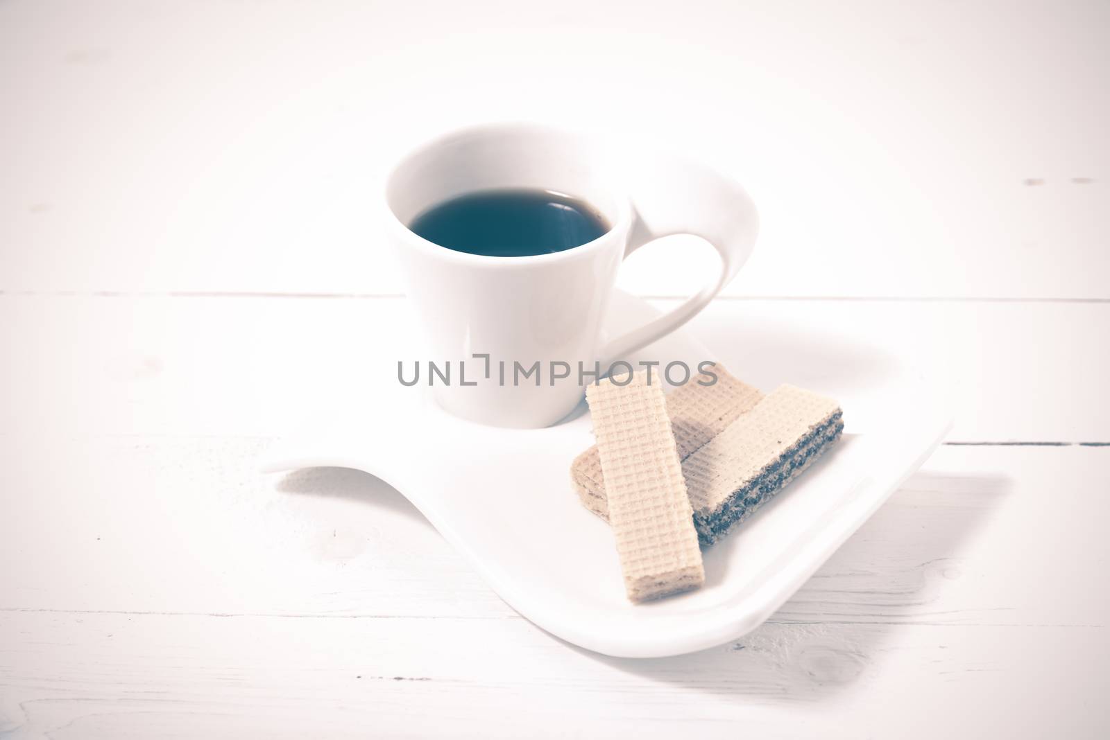 coffee cup with wafer on white wood background vintage style