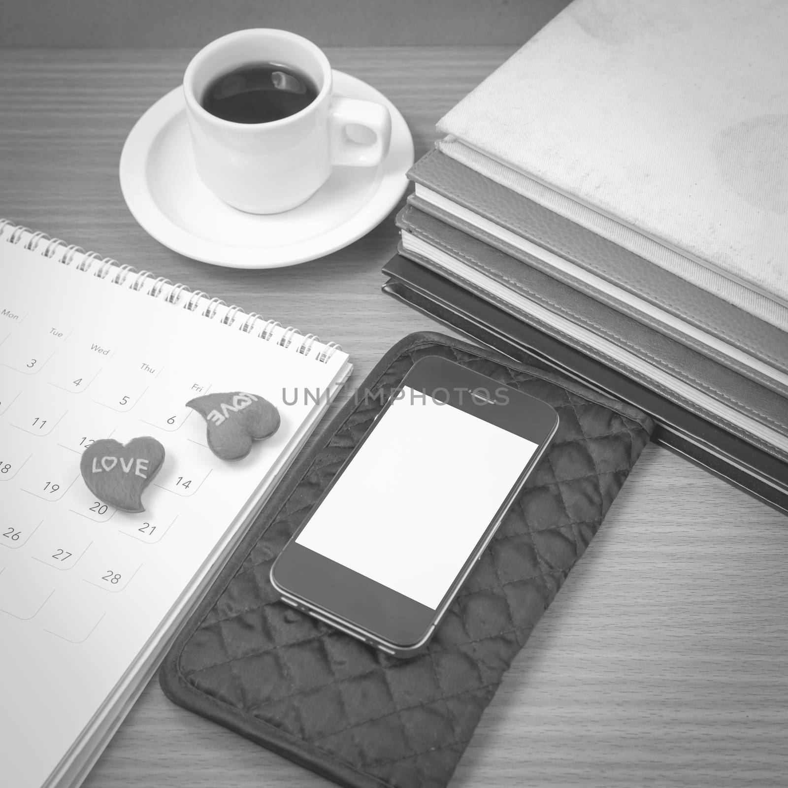 office desk : coffee with phone,wallet,calendar,heart,stack of book on wood background black and white color