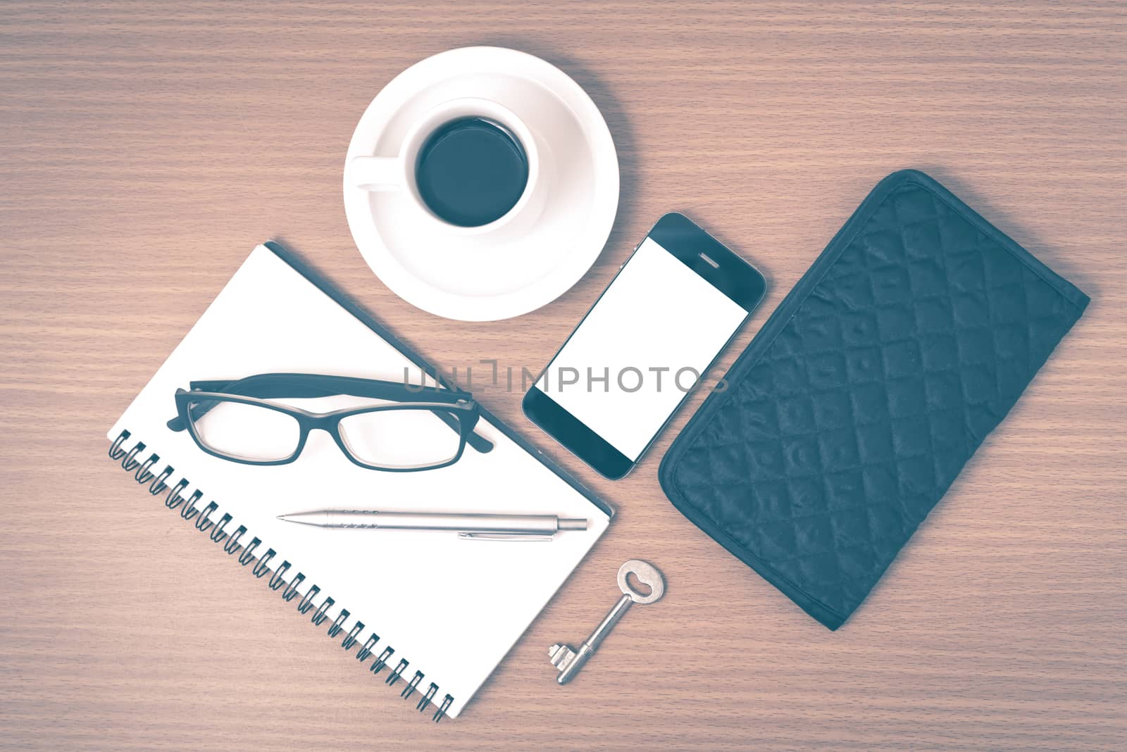 coffee and phone with notepad,key,eyeglasses and wallet on wood table background vintage style