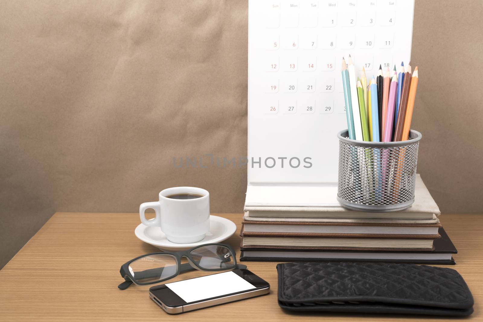 office desk : coffee with phone,wallet,calendar,color pencil box,stack of book,eyeglasses on wood background