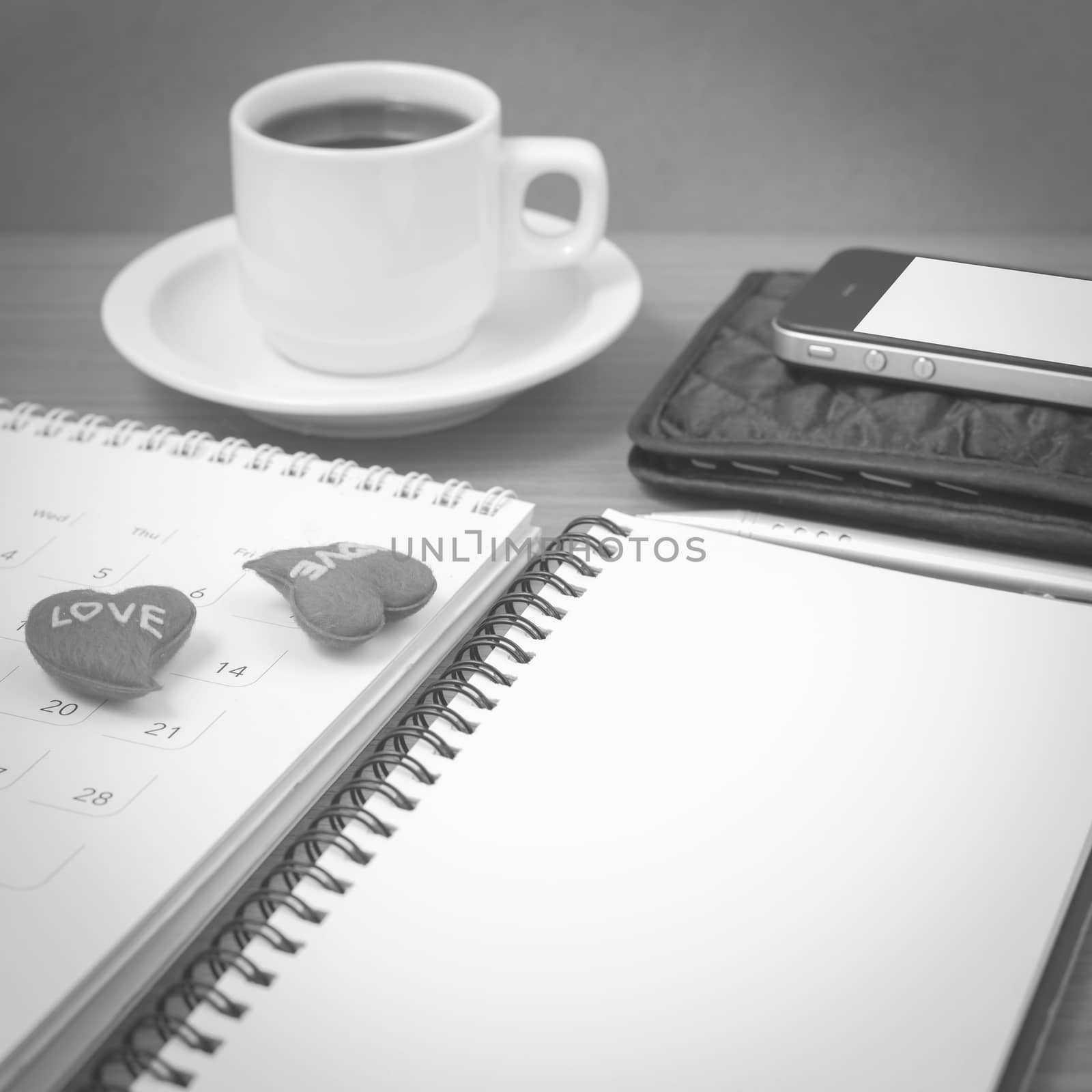 office desk : coffee with phone,wallet,calendar,heart,notepad on wood background black and white color