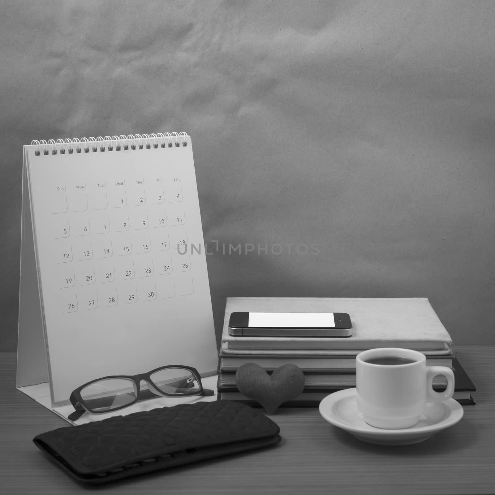 desktop : coffee with phone,stack of book,wallet,heart,eyeglasses,calendar on wood background black and white color