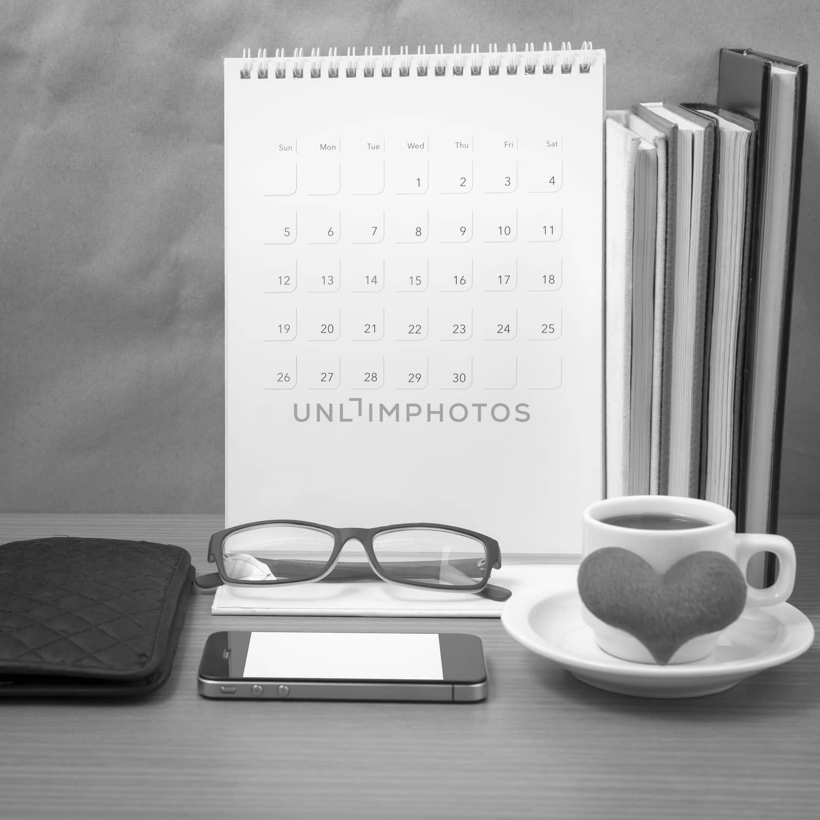 desktop : coffee with phone,stack of book,wallet,heart,eyeglasses,calendar on wood background black and white color