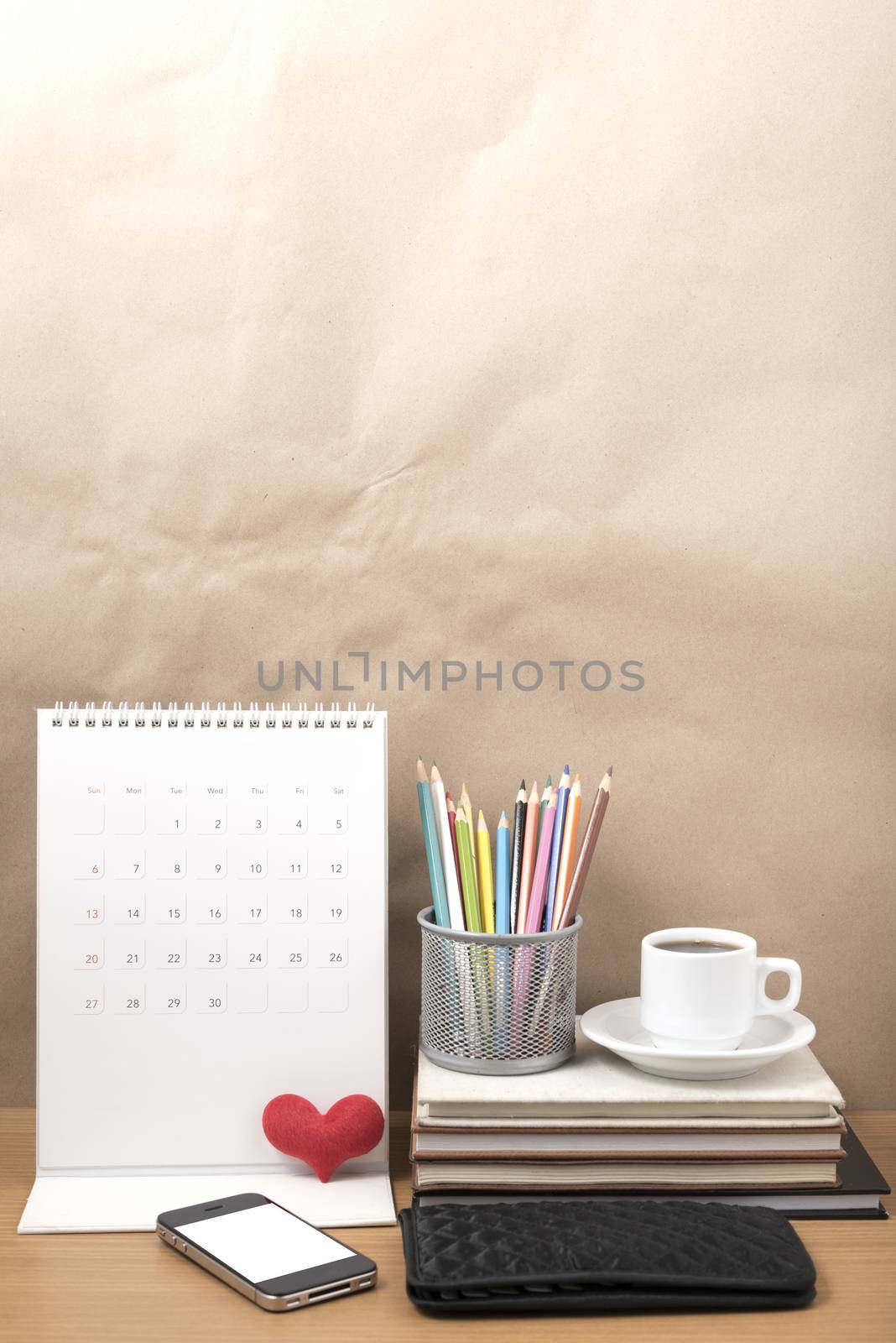 office desk : coffee with phone,wallet,calendar,heart,color pencil box,stack of book,heart on wood background