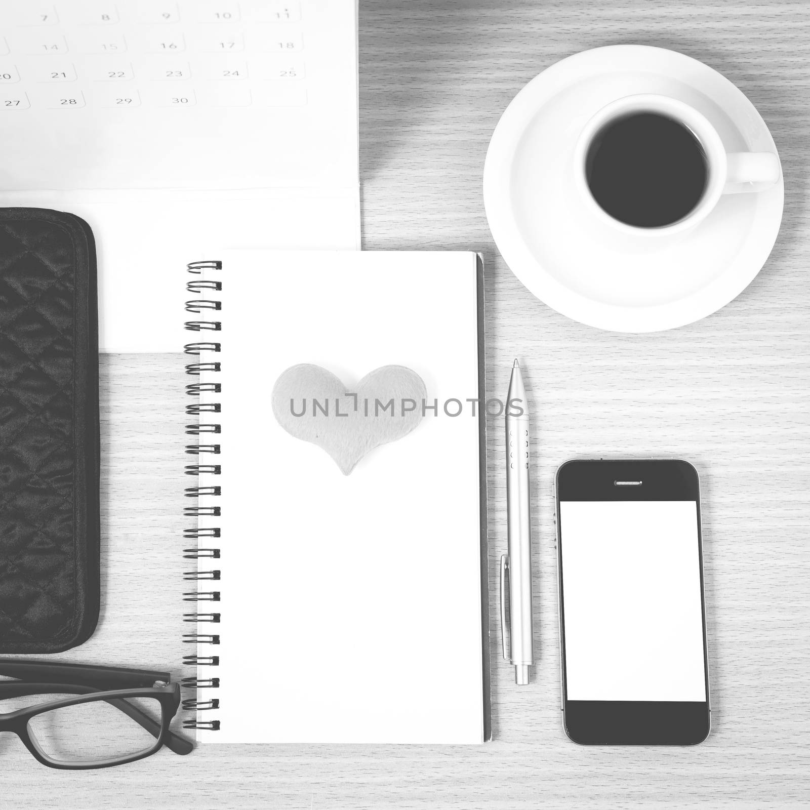 office desk : coffee with phone,wallet,calendar,heart,notepad,eyeglasses,heart on wood background black and white color